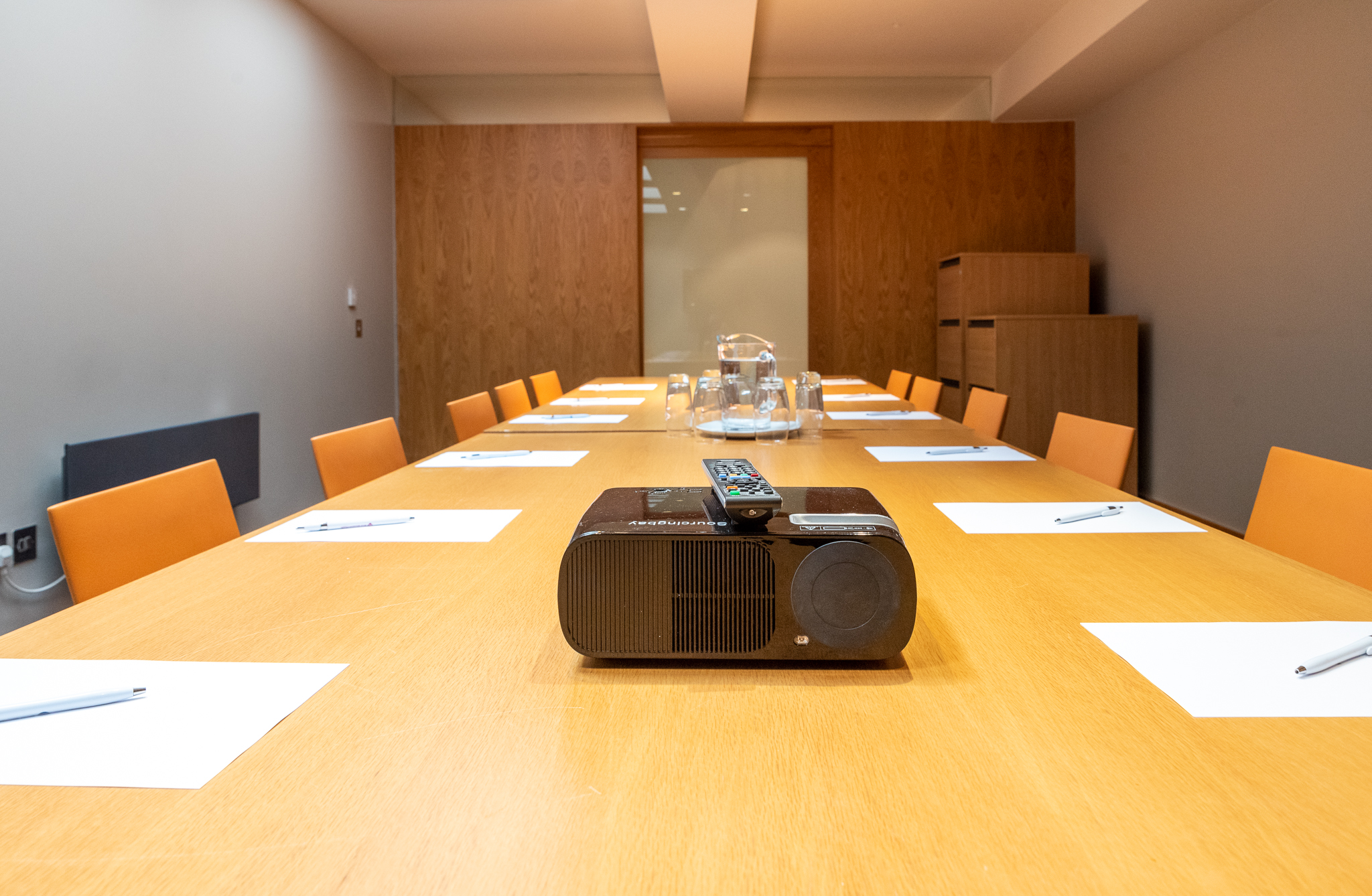 Modern conference room with wooden table and orange chairs, ideal for professional meetings.