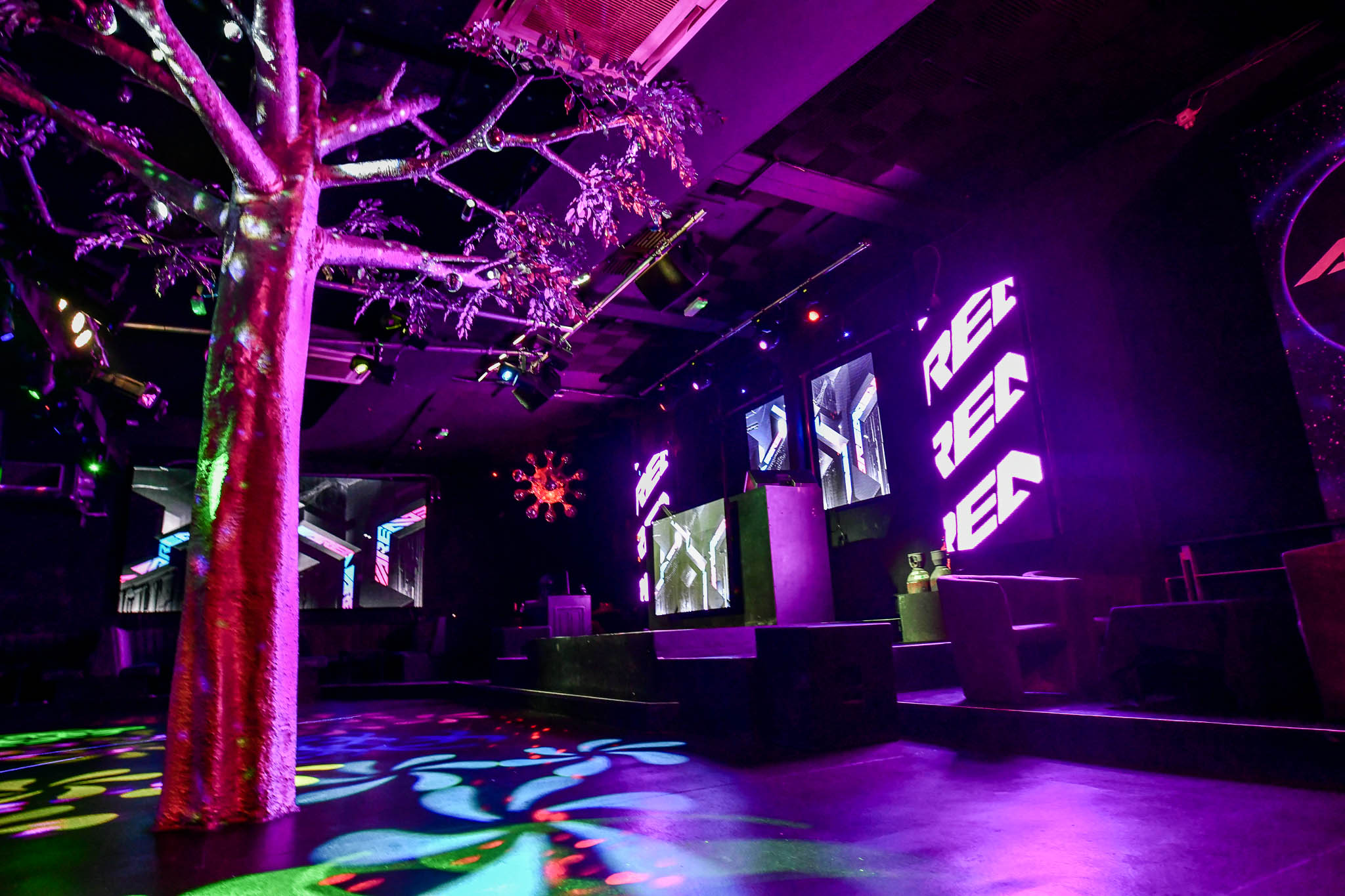 Vibrant event space in Manchester with dynamic lighting and unique tree installation.