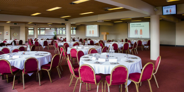 Knighton Suite at Yarnfield Park, elegant conference space with round tables and red chairs.