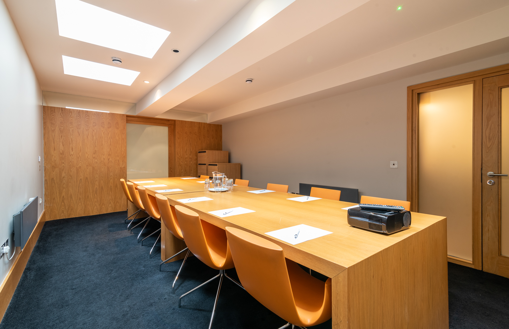 Modern conference room with wooden table and orange chairs for meetings and brainstorming.