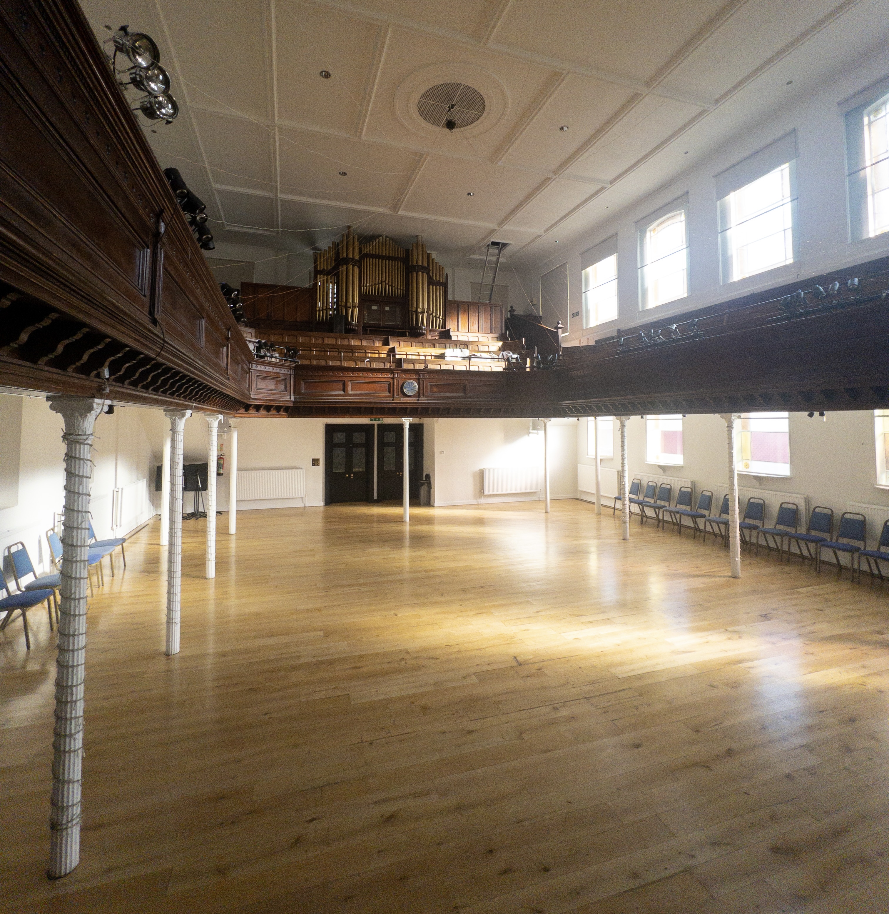 Spacious event venue with polished floors and balcony, perfect for meetings and workshops.