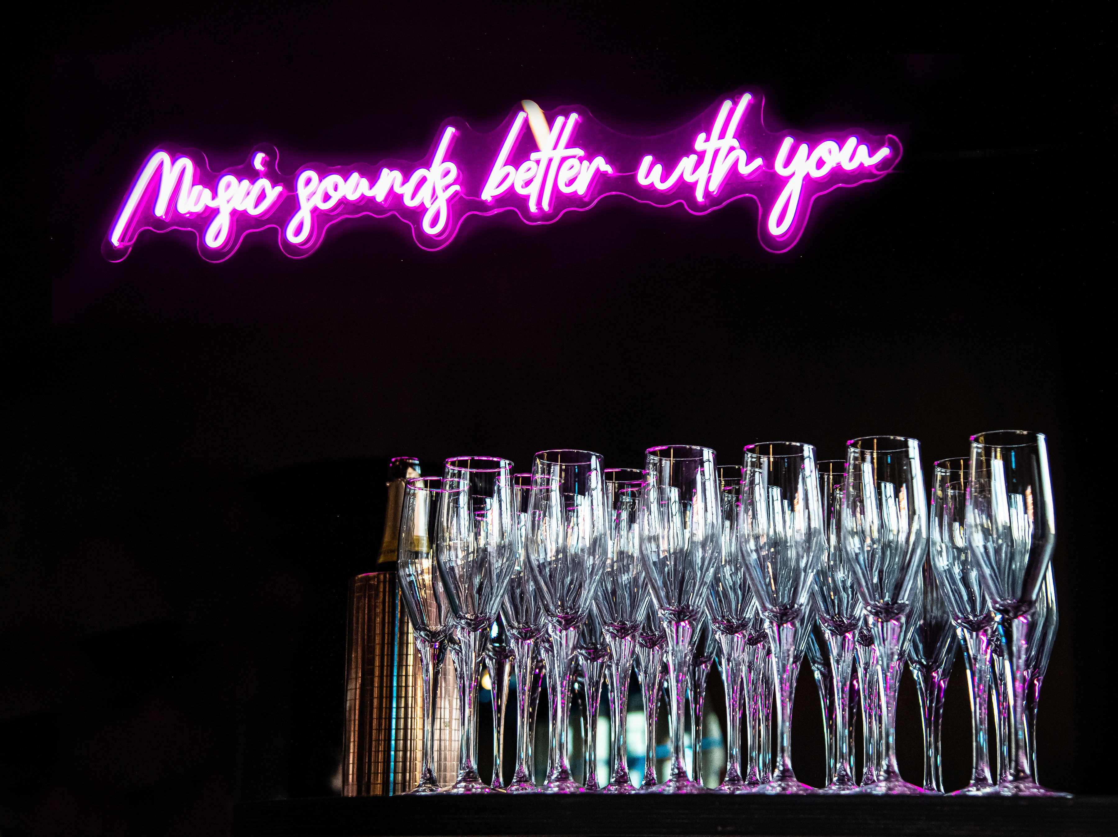 Vibrant event space with neon sign and champagne flutes for upscale celebrations.
