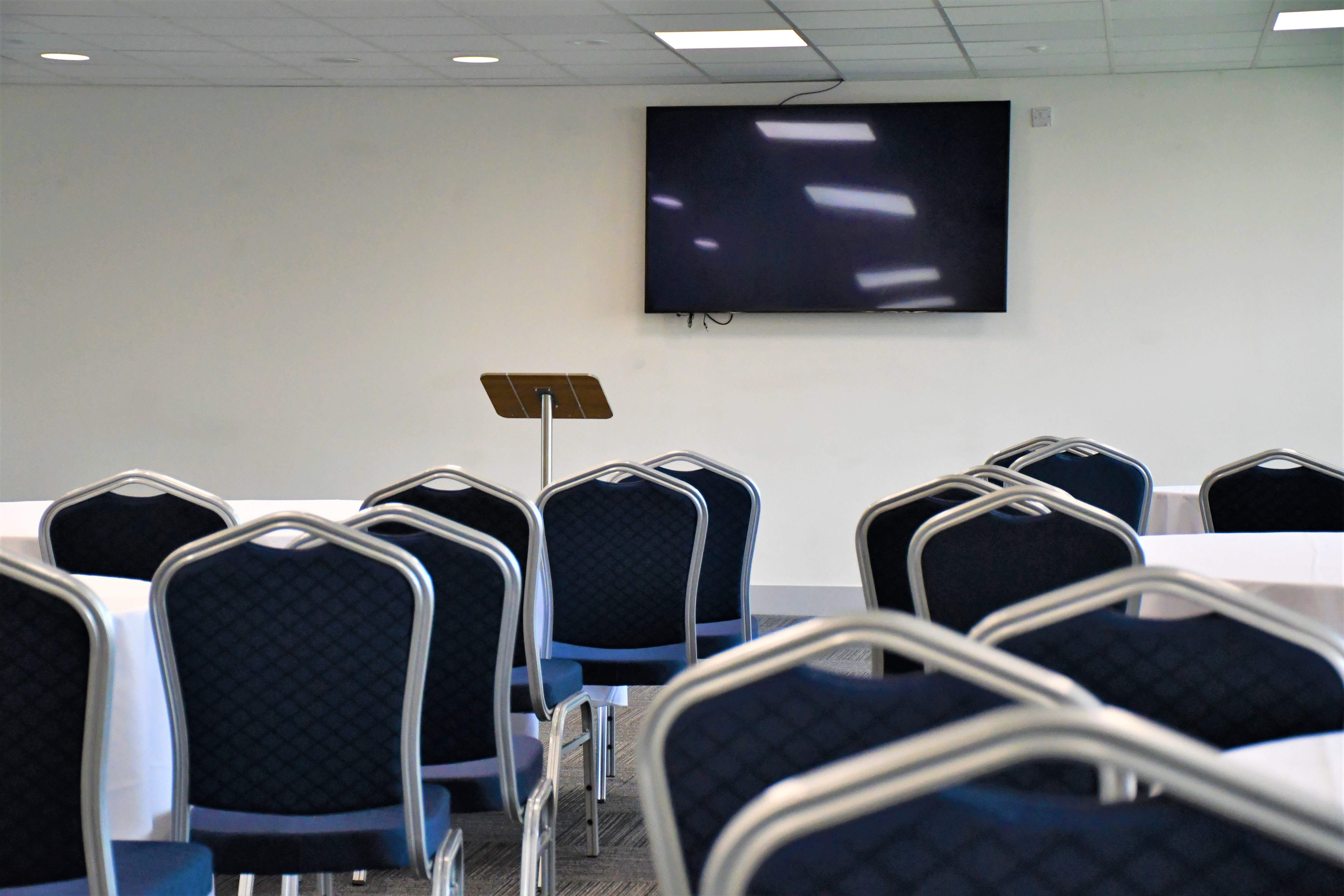 Platinum Lounge meeting space with chairs, podium, and screen for professional events.