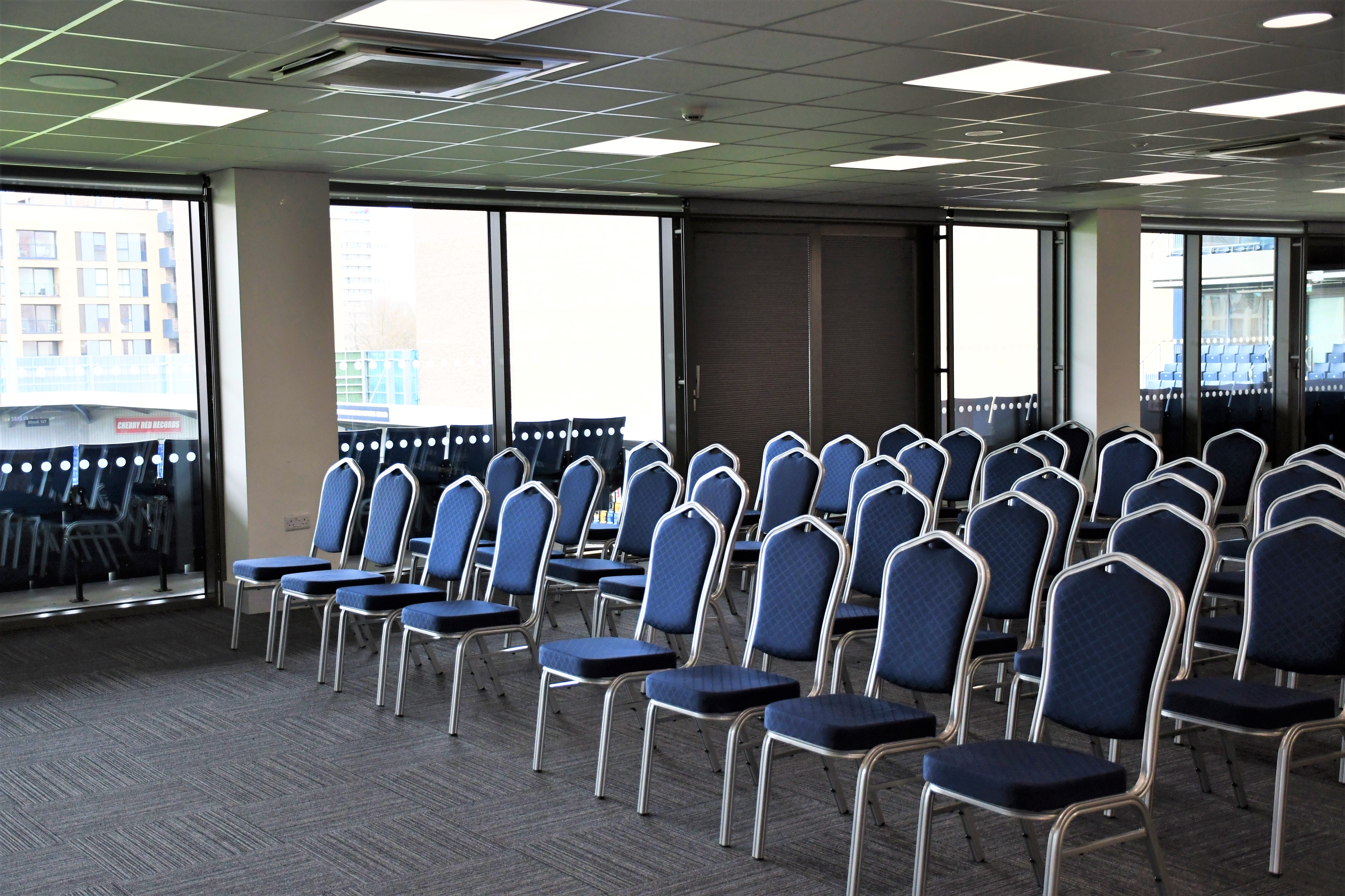 Platinum Lounge at AFC Wimbledon: bright meeting space with blue chairs for workshops.