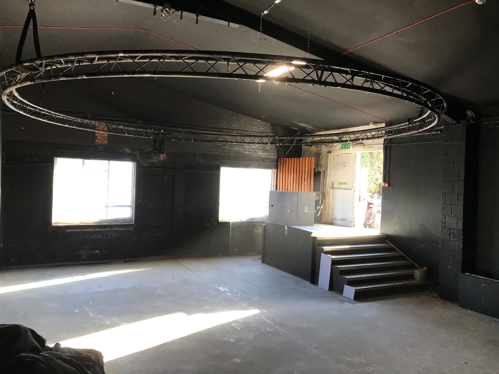 Versatile industrial event space with natural light and circular truss for presentations.