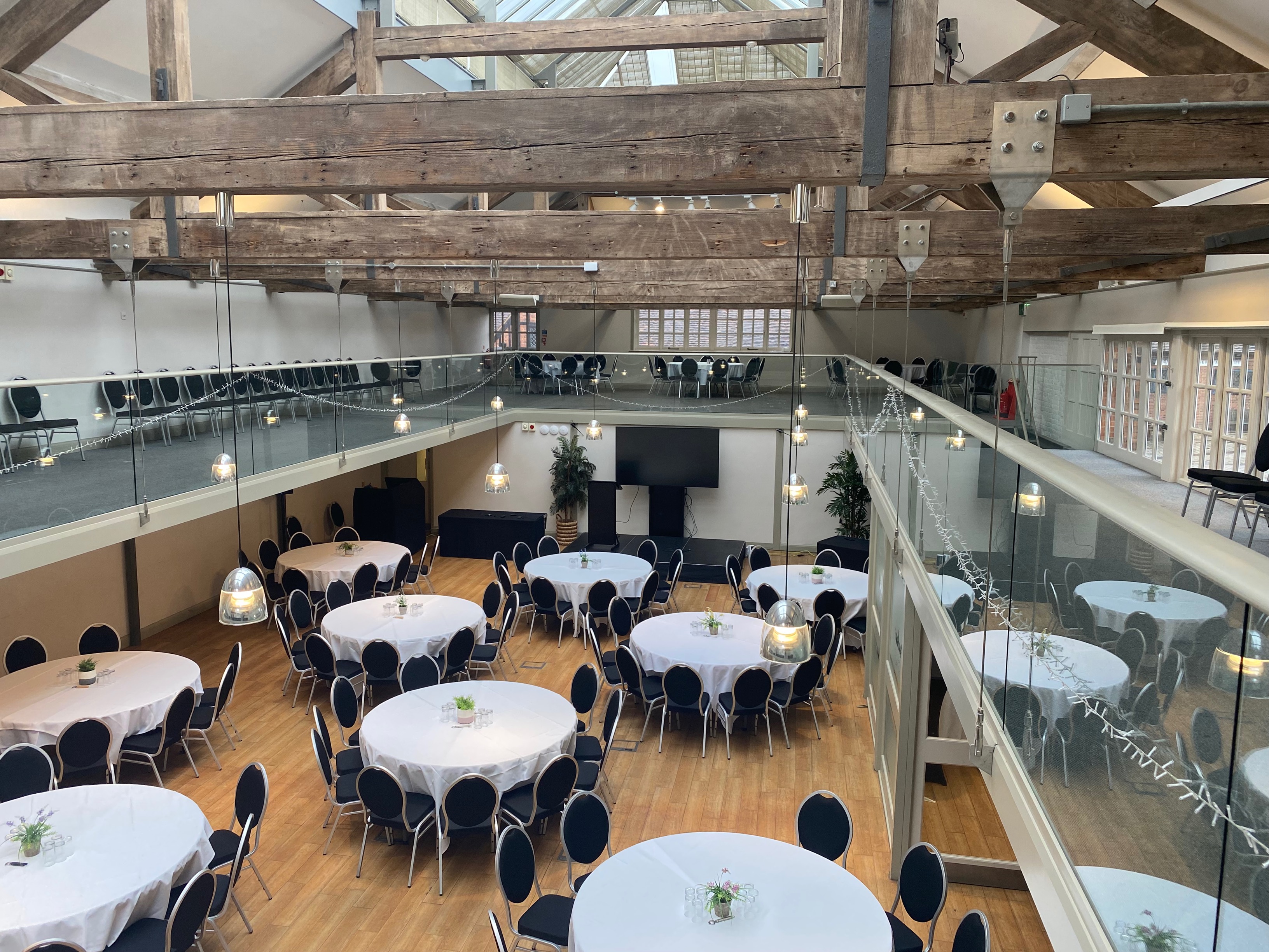 Elegant Riding School venue with round tables, ideal for conferences and weddings.