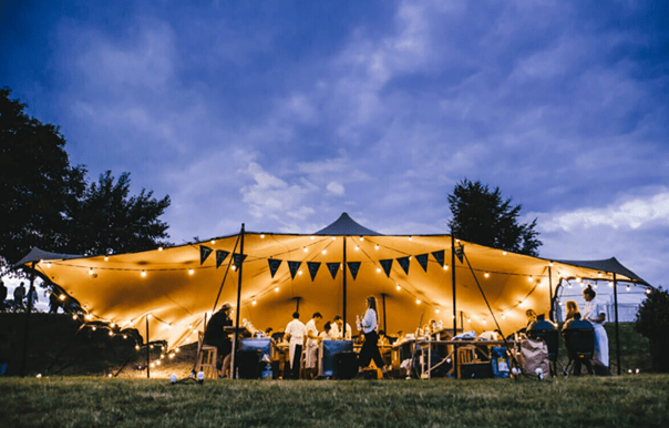 Outdoor wedding event at Hatfield House with illuminated tent and festive bunting.