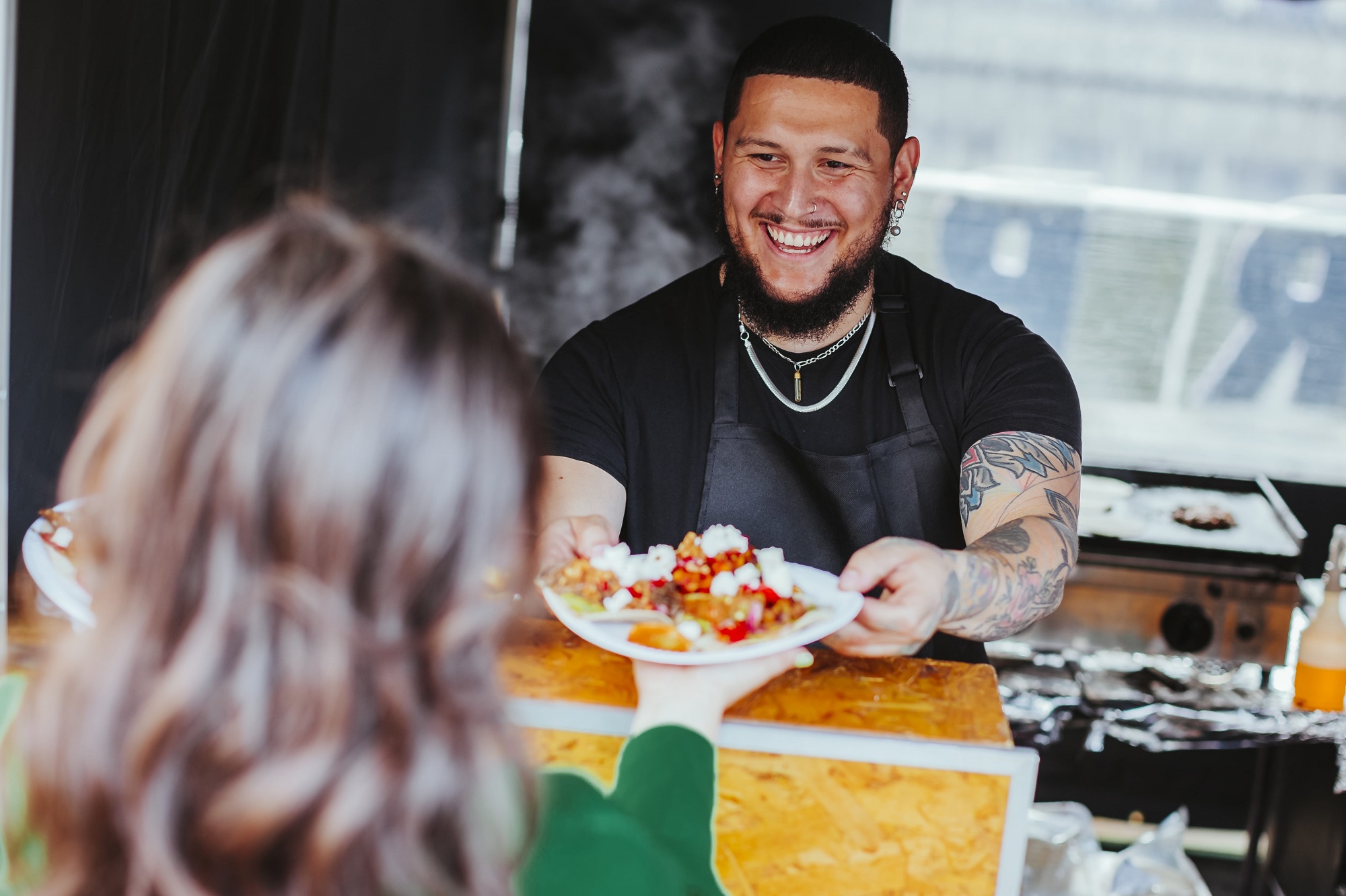 Smiling chef serves beautifully plated dish at Hatfield House event, enhancing guest experience.