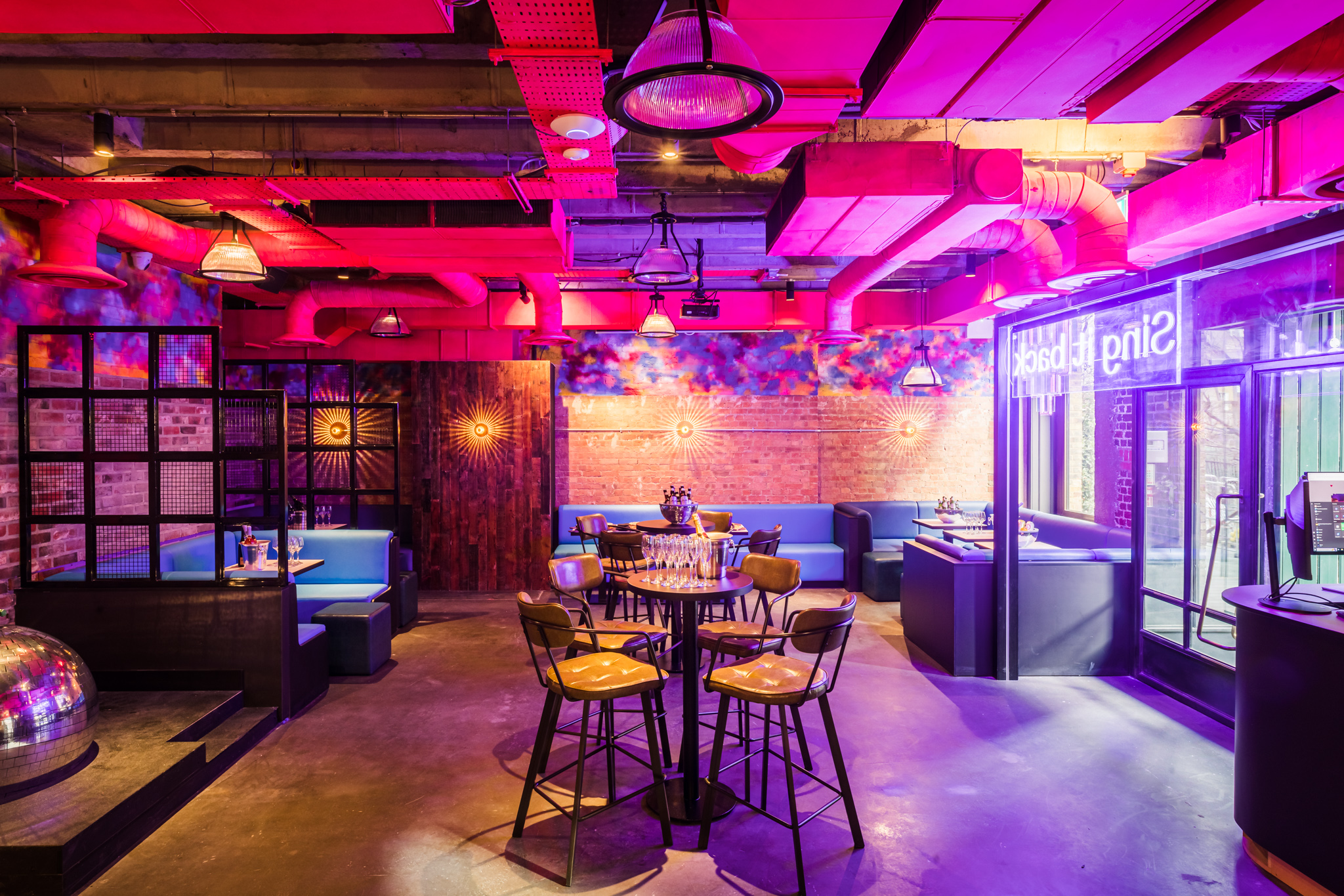 Vibrant event space at Lucky Voice Liverpool Street with bold pink lighting for gatherings.