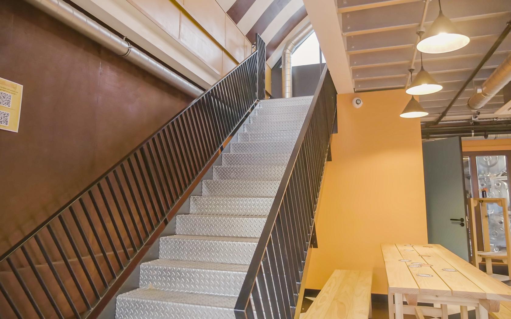 "Well-lit staircase in modern industrial brewery, ideal for networking events."