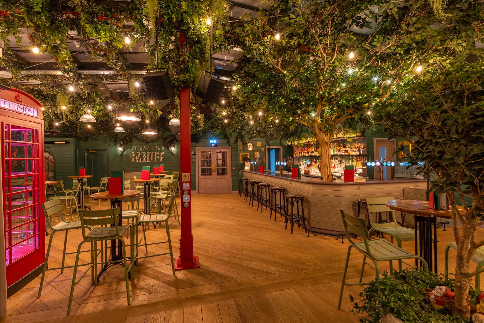 "Vibrant event space in Flight Club Cardiff with lush greenery, ideal for networking events."
