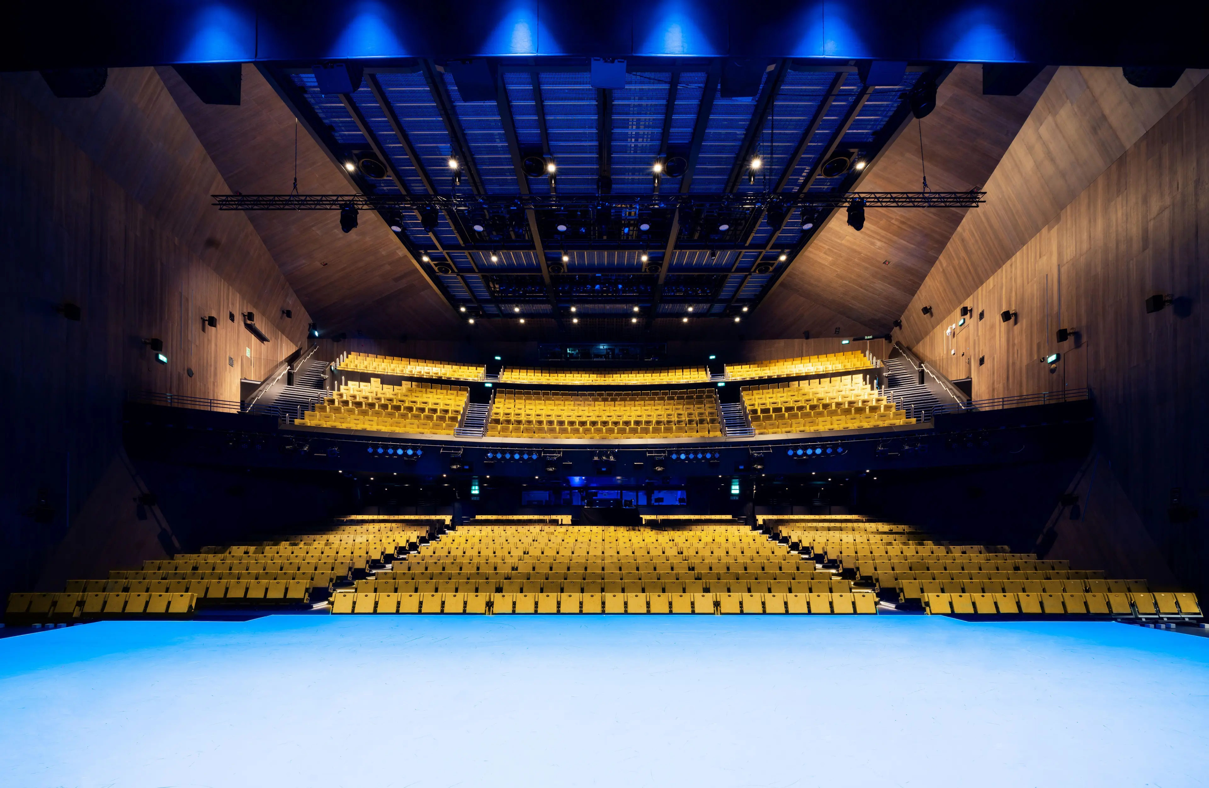 Modern auditorium with tiered seating and bright yellow chairs for conferences and presentations.