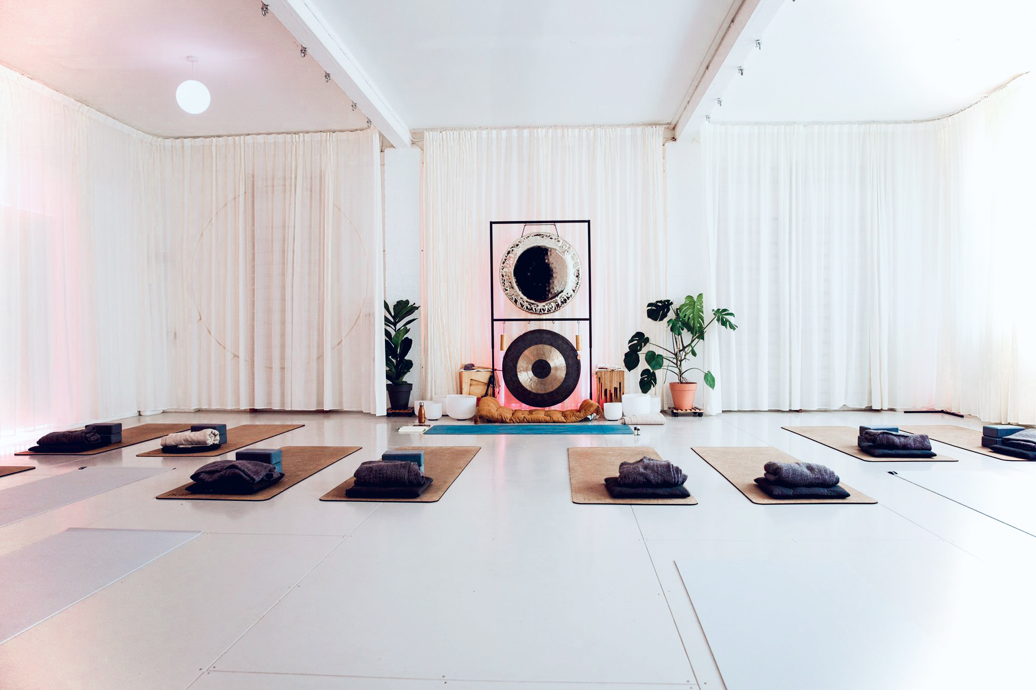 Serene wellness event space with yoga mats and a large gong for mindfulness retreats.
