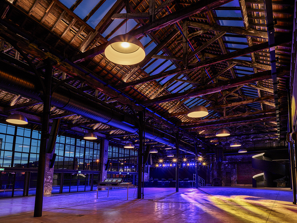Spacious industrial event venue with high ceilings, ideal for corporate and social gatherings.