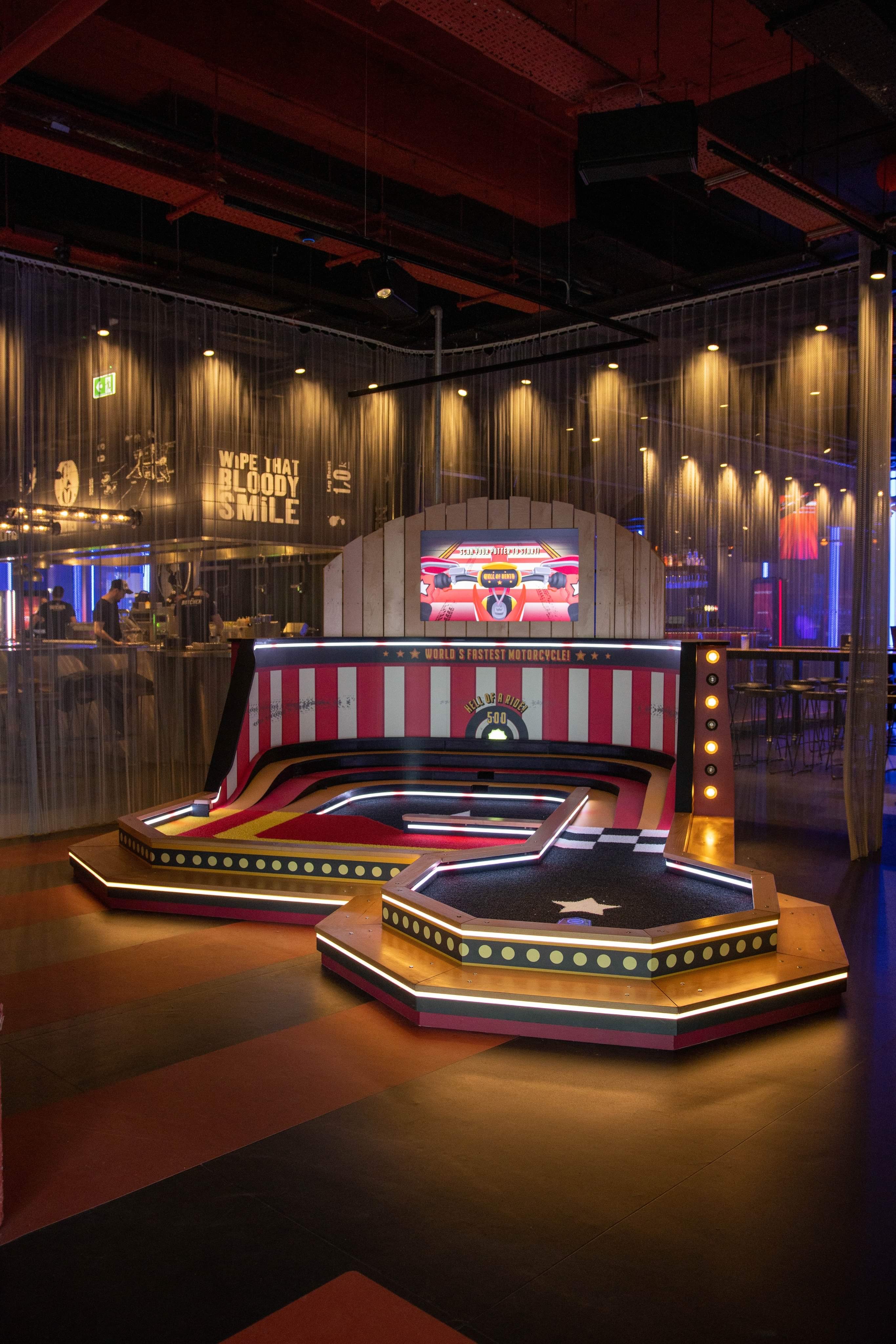 "Putters Tech mini golf venue with vibrant stage for interactive events and networking."