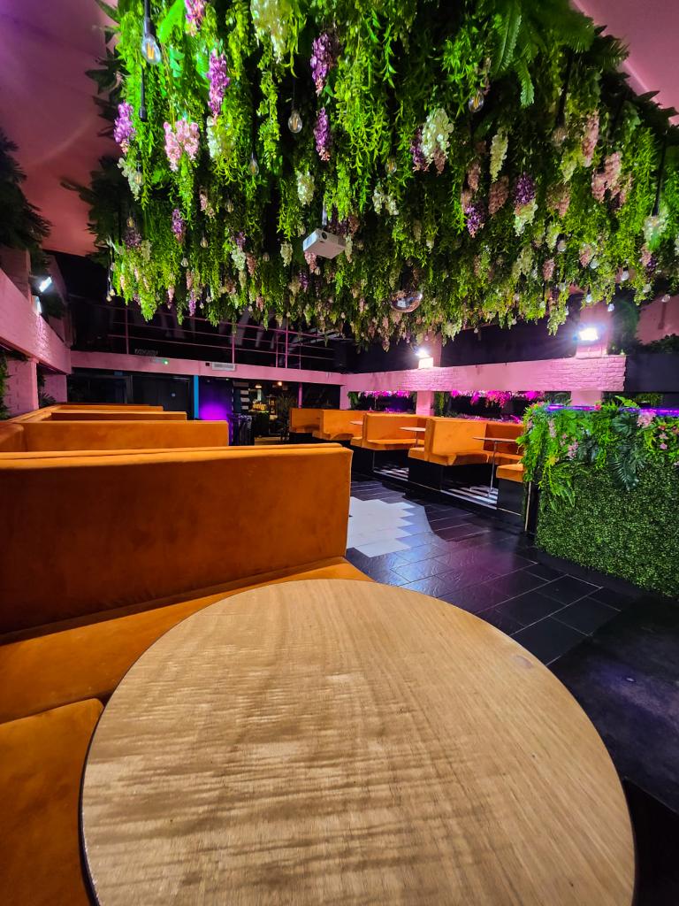VIP area with cozy orange booths and lush greenery at BUNA Lounge & NightClub.
