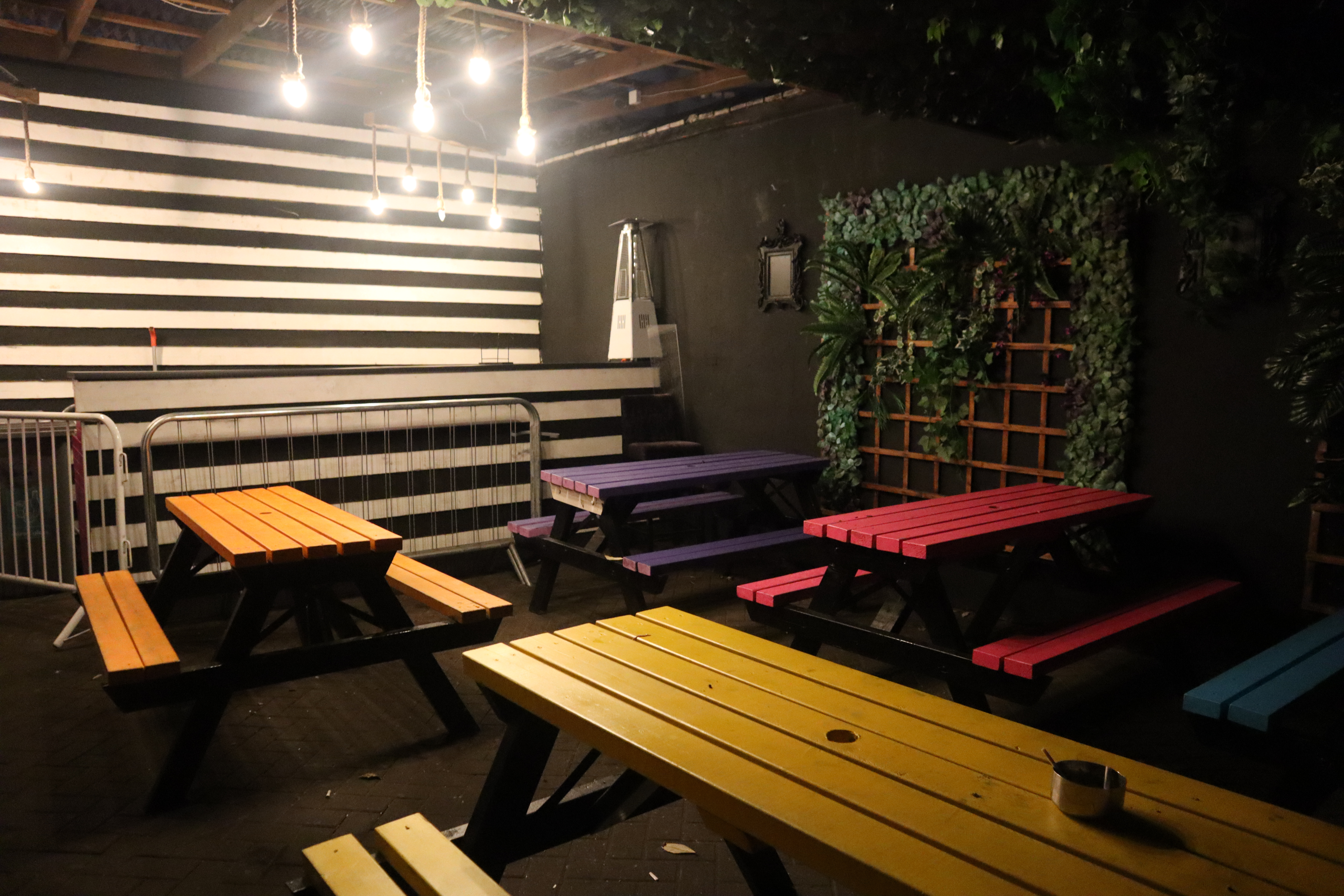 Vibrant outdoor event space with colorful picnic tables at BUNA Lounge & NightClub.