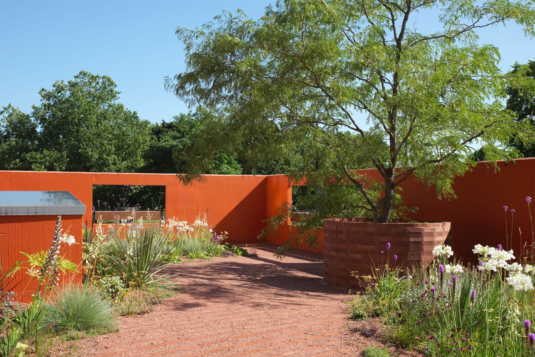 Vibrant outdoor event space at Forma HQ with warm orange walls and lush greenery.