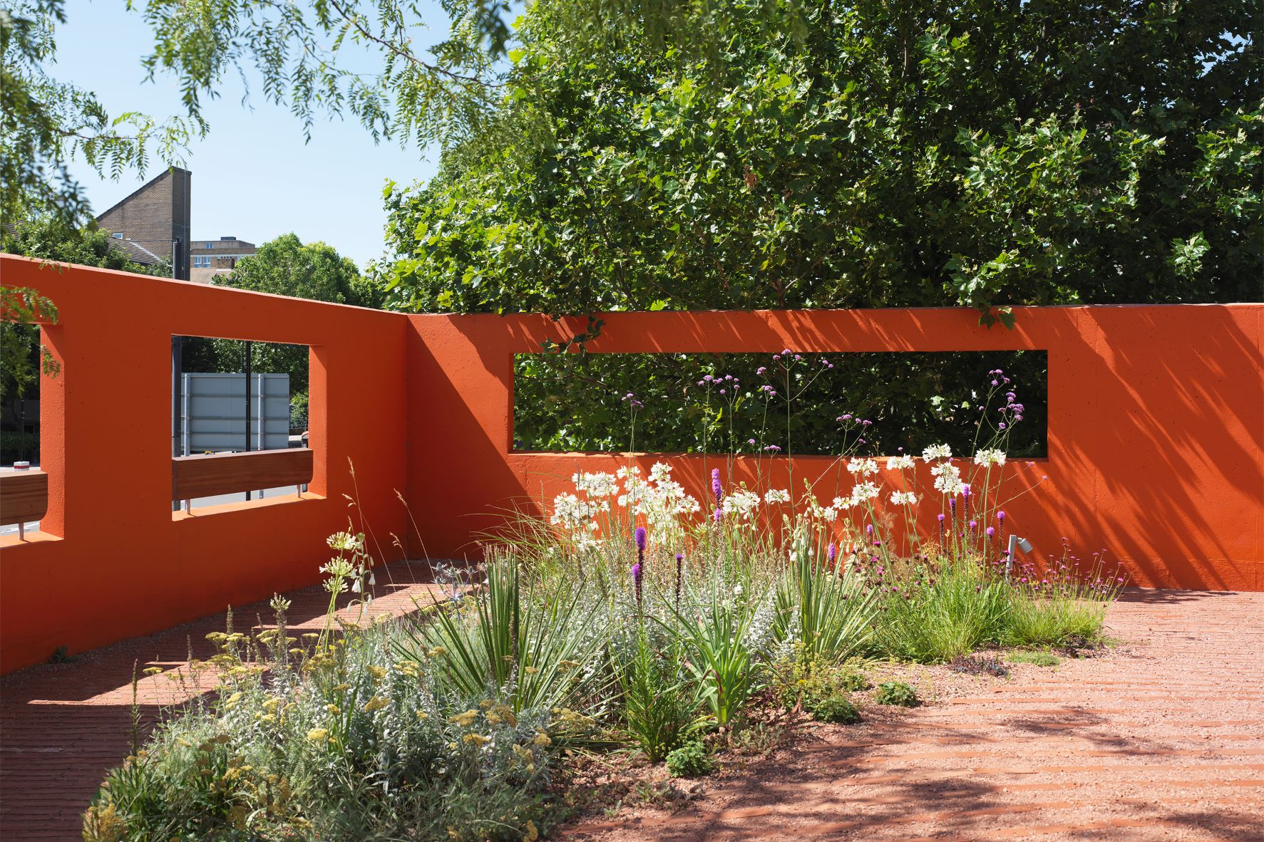 Vibrant outdoor event space at Forma HQ with orange wall and lush greenery.
