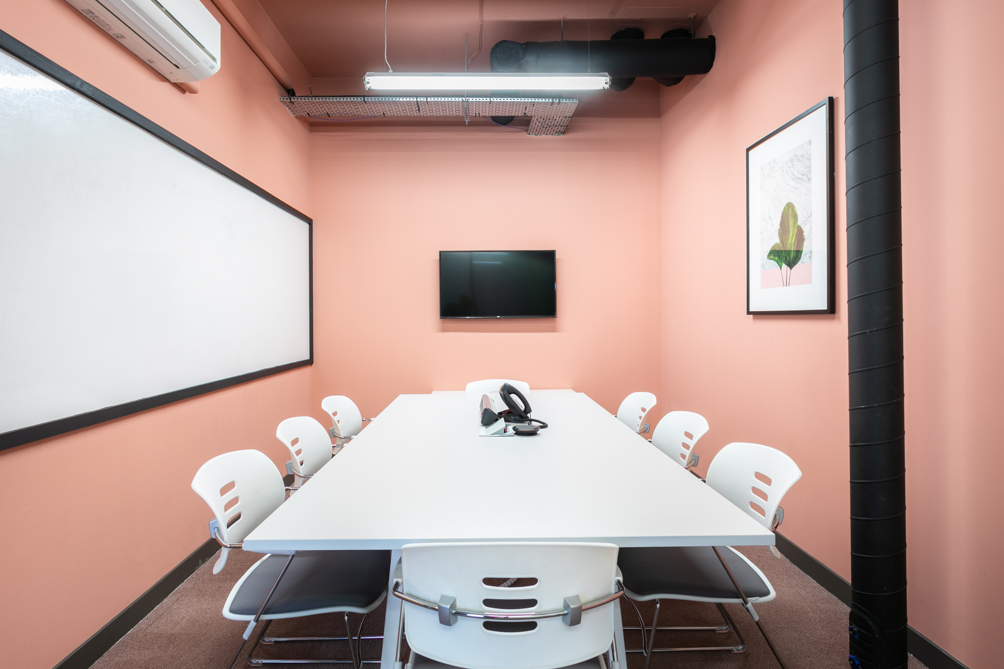 Modern meeting room with peach walls, ideal for collaborative sessions at Moneypenny Workhub.