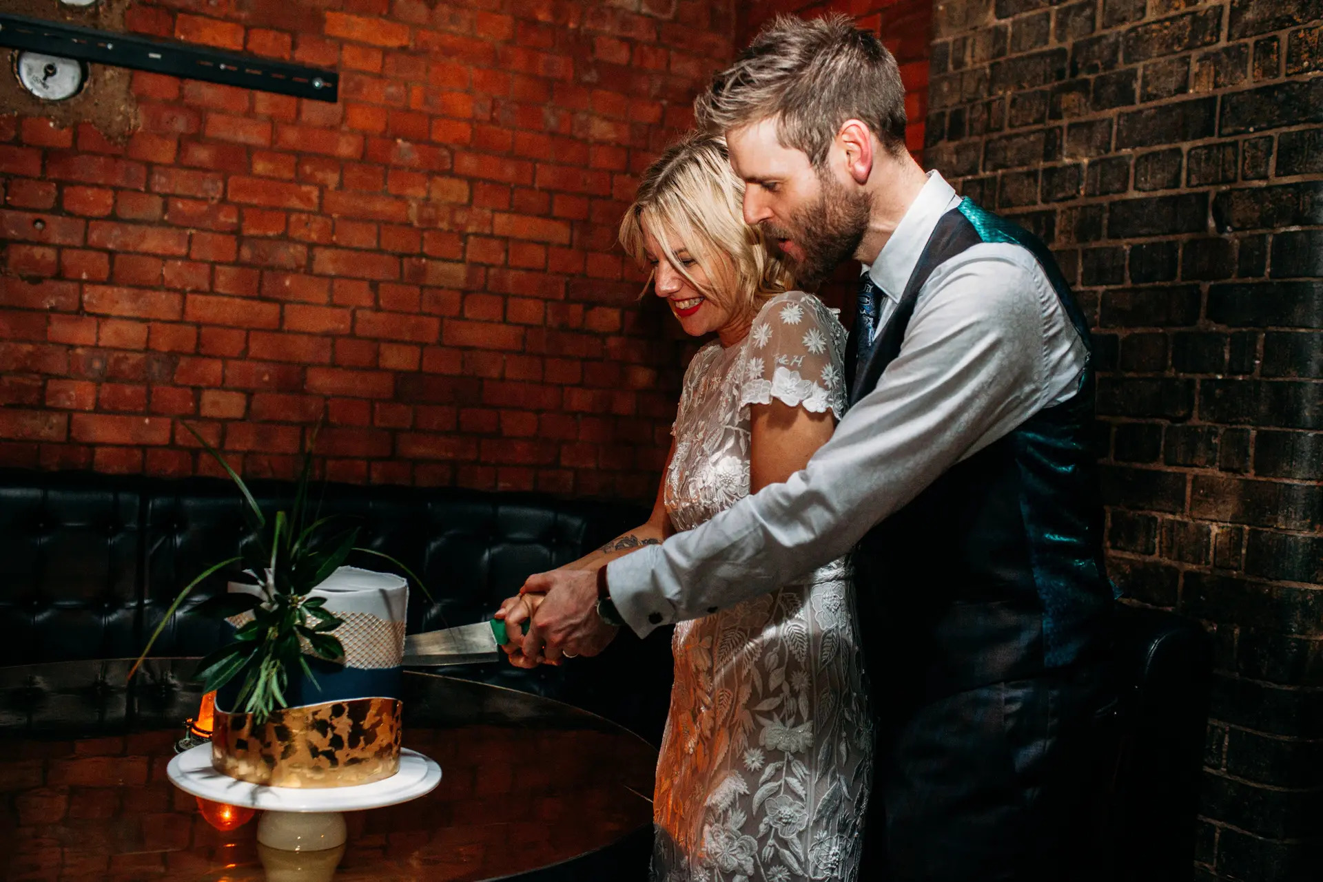 Couple cutting cake in warm, stylish Singer Tavern for a memorable celebration event.