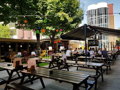 Vibrant outdoor event space with picnic tables for casual gatherings and networking.