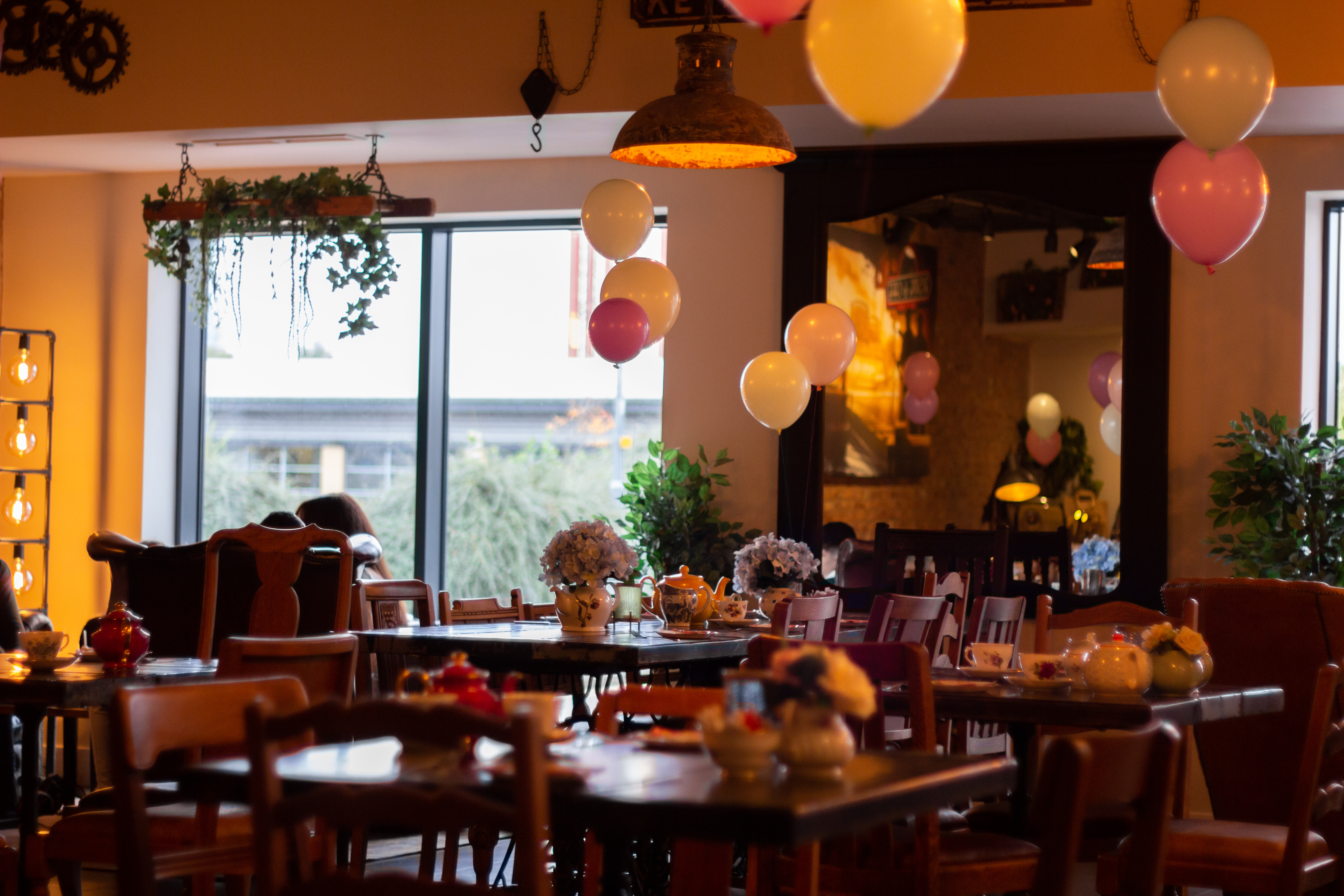 Rising Cafe event space with warm lighting, balloons, and floral decor for gatherings.