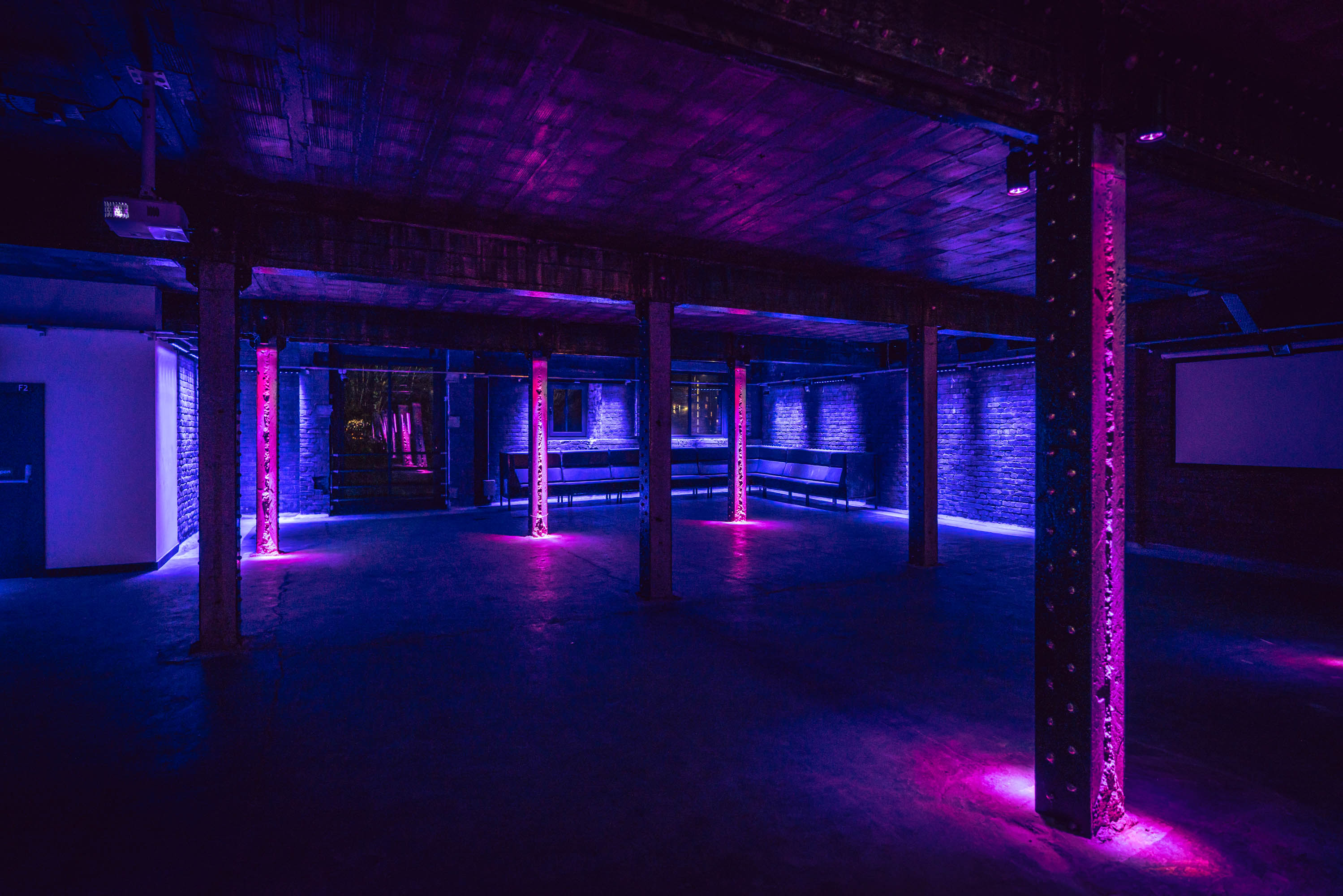 Tobacco Stores event space with exposed beams and purple lighting for creative gatherings.