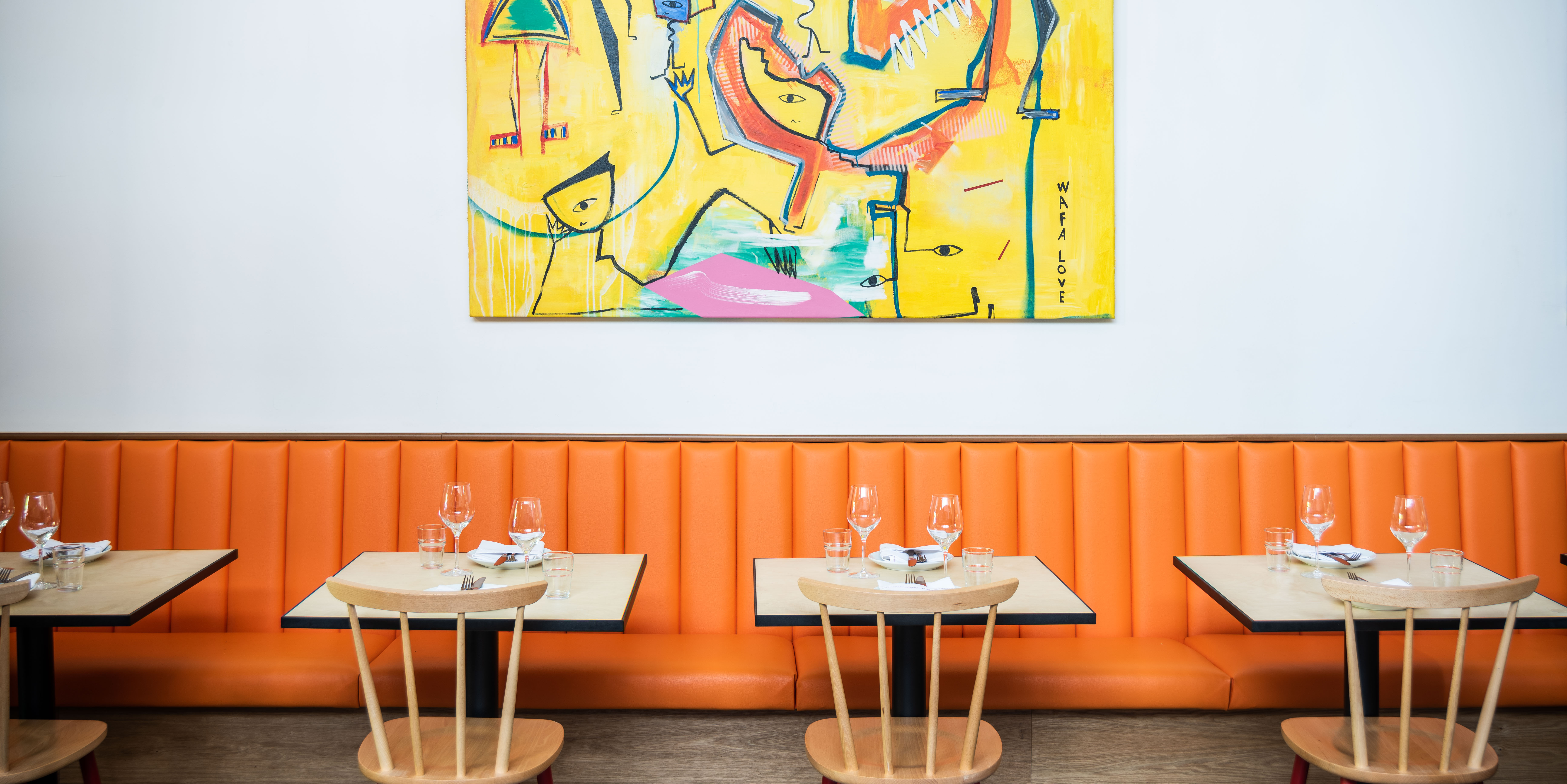Vibrant dining space with orange banquette for creative meetings and intimate events.