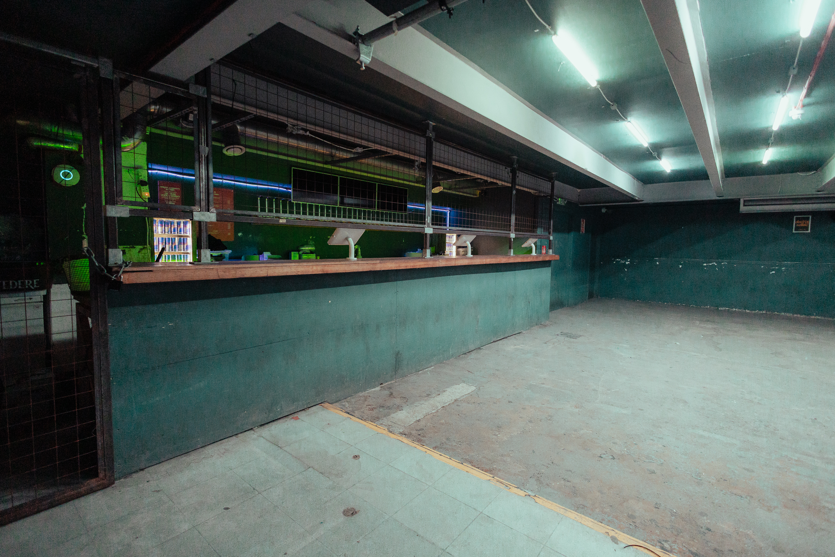 Spacious industrial venue with green lighting, ideal for creative events and gatherings.