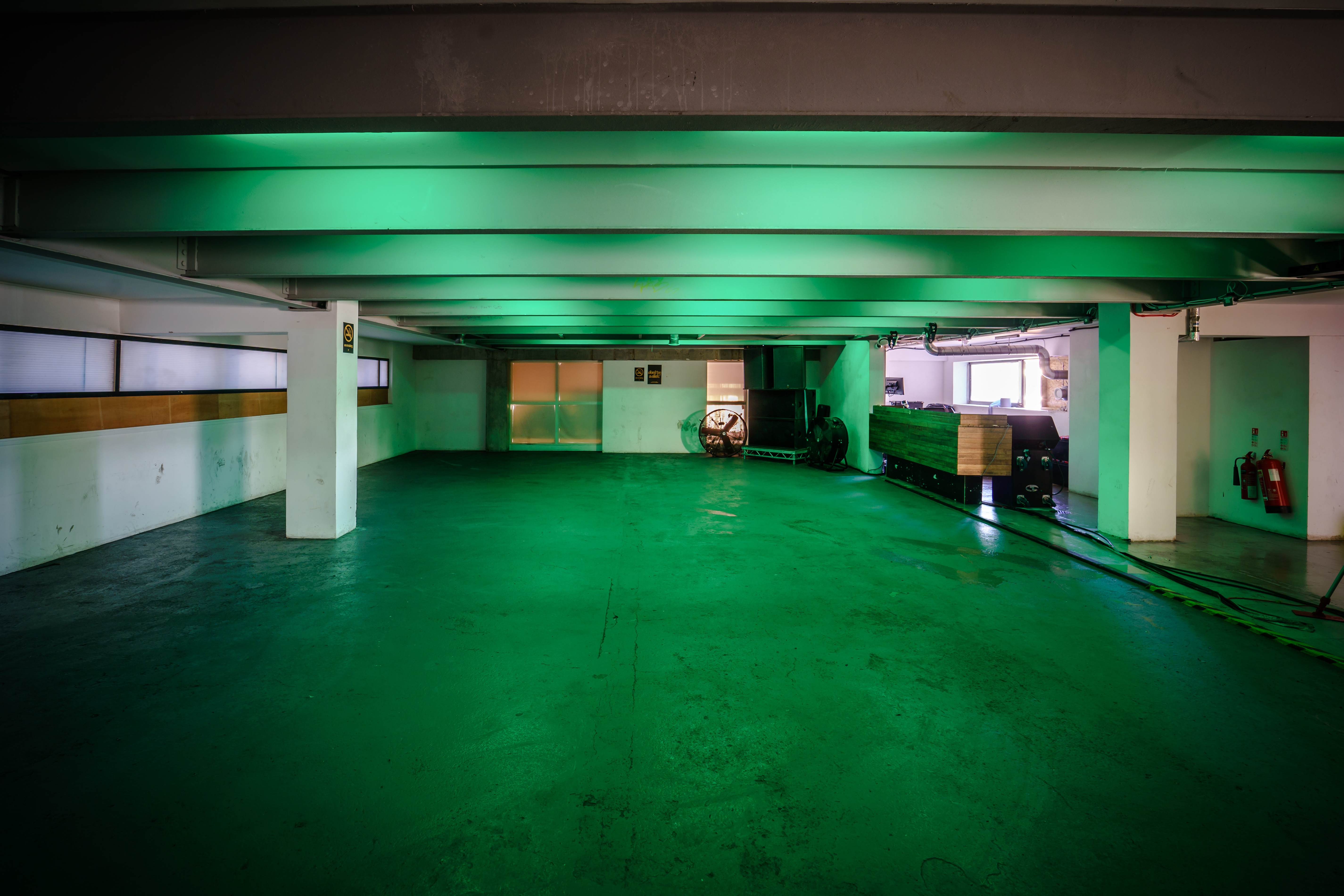 Versatile industrial event space with green lighting at The Cause, perfect for gatherings.