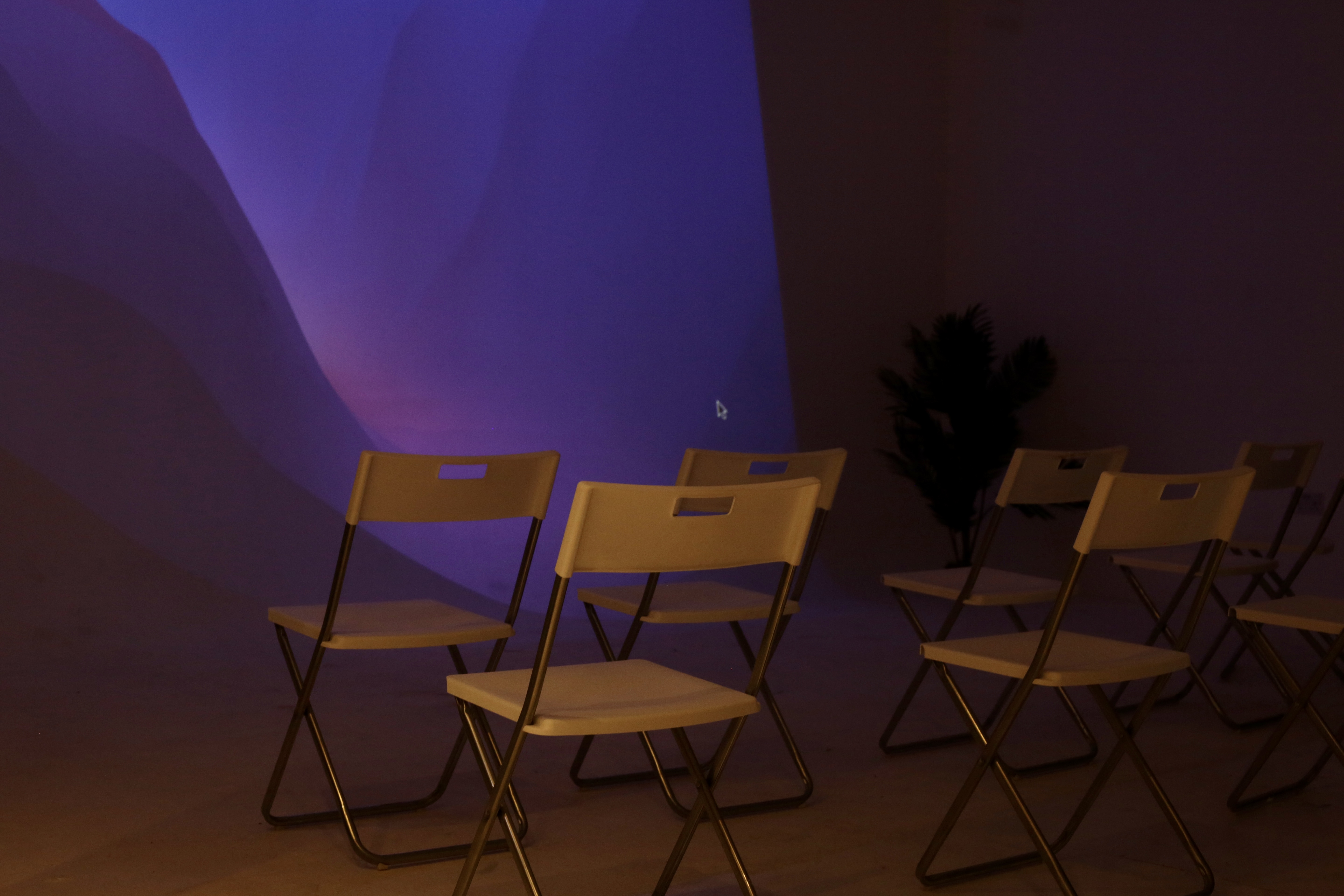 Minimalist white meeting room with folding chairs for intimate workshops and discussions.