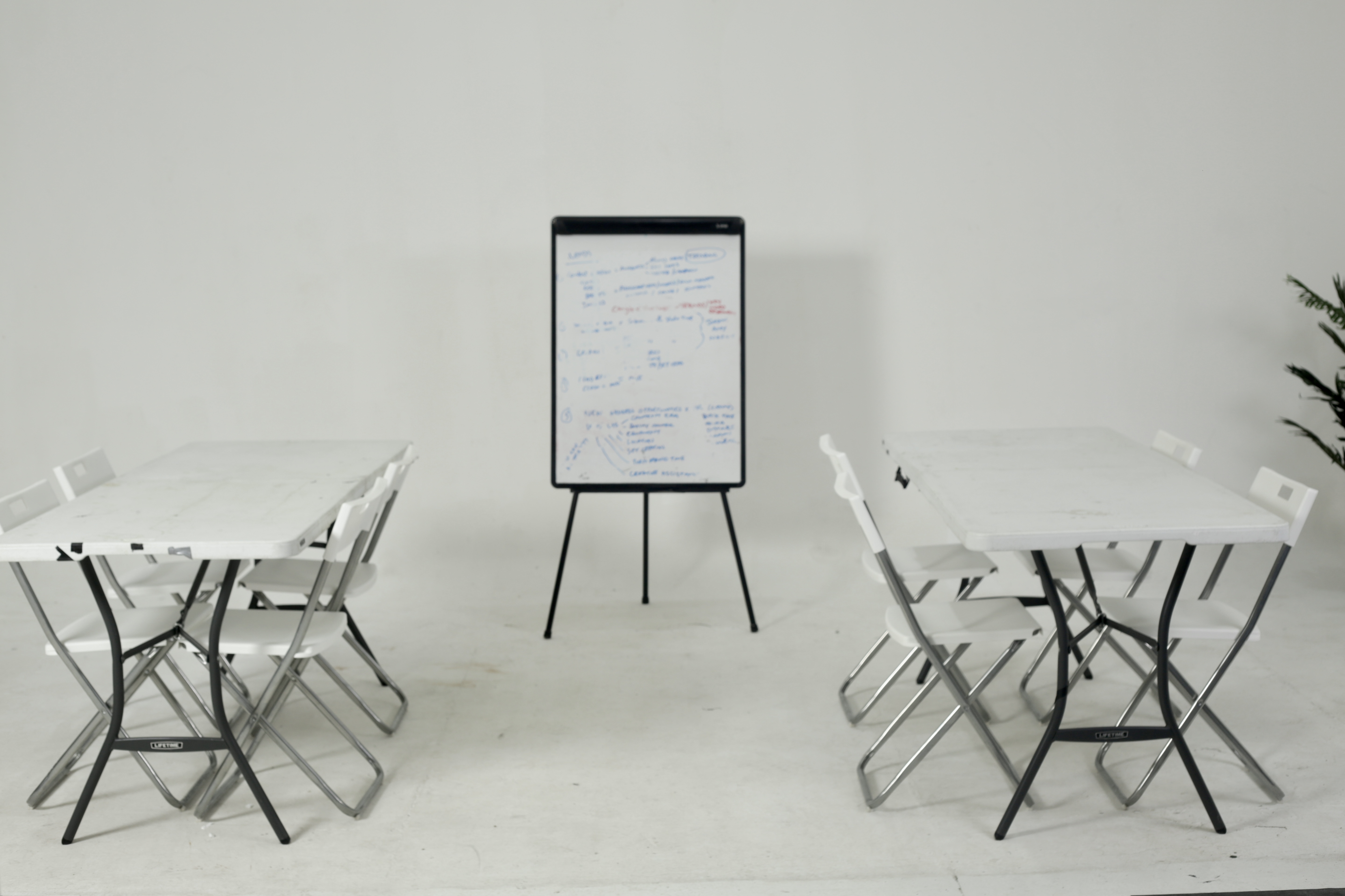 Minimalist meeting room with folding tables and flip chart for workshops and strategy sessions.