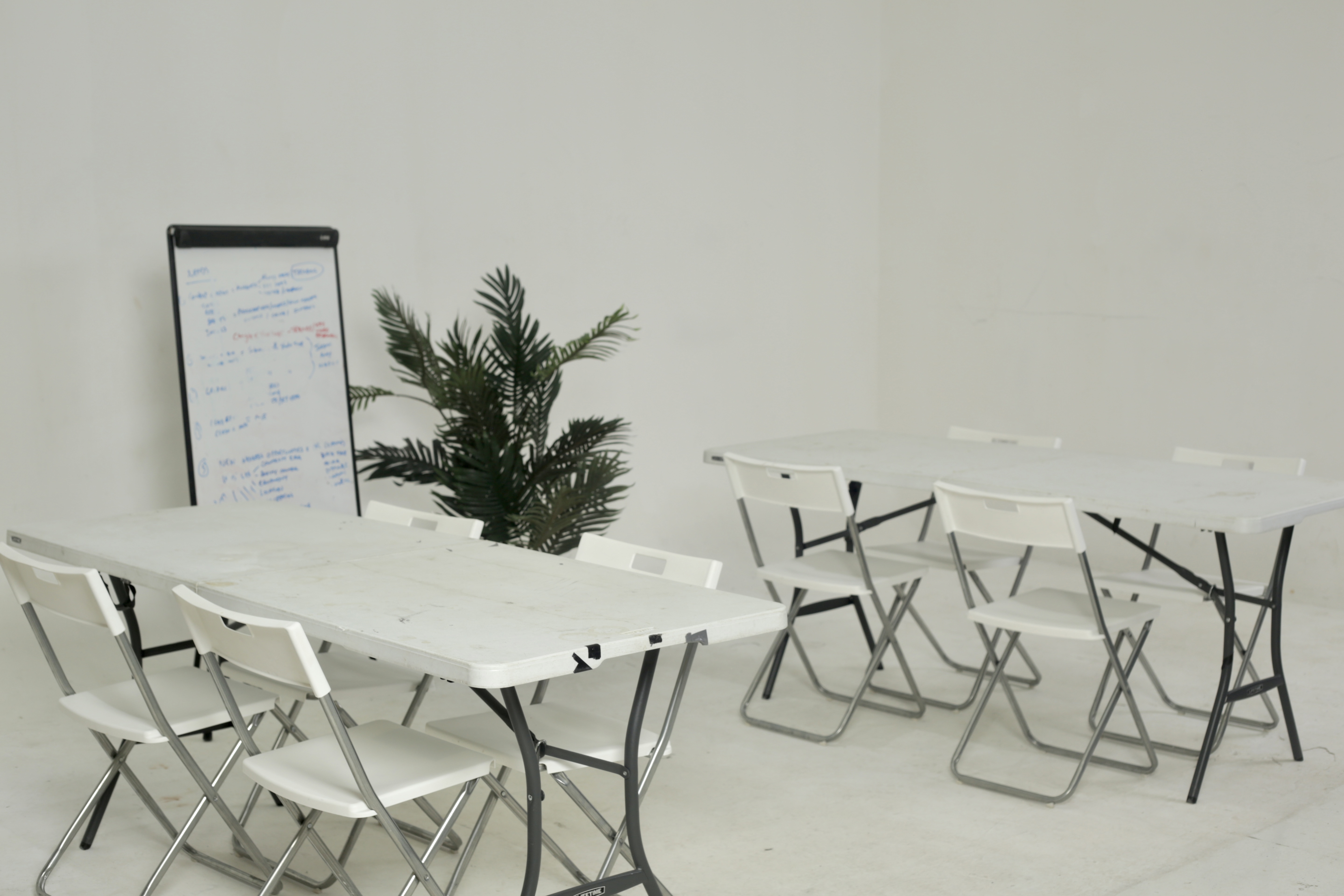 Minimalist white meeting room with folding tables for workshops and brainstorming sessions.