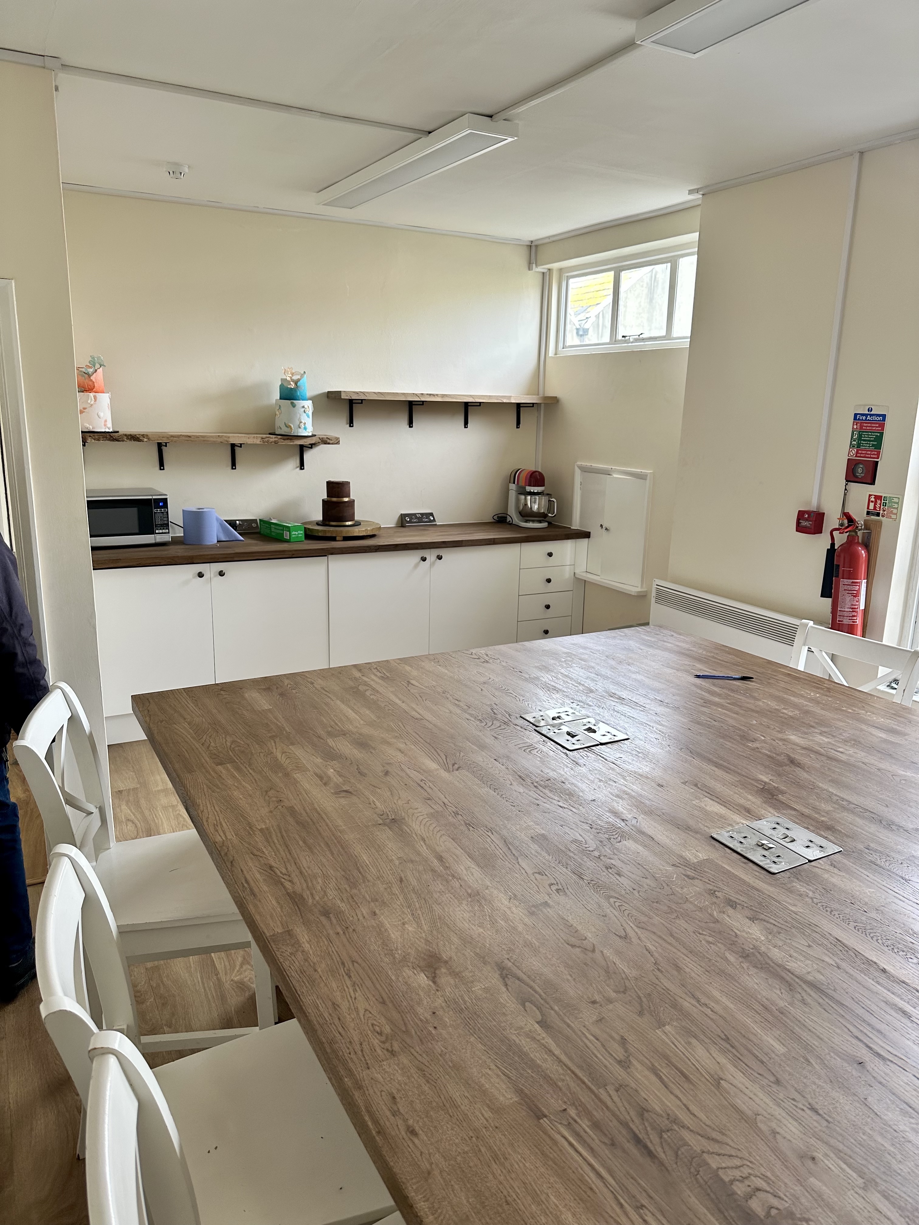 "Modern meeting space with wooden table and kitchenette for collaborative sessions"