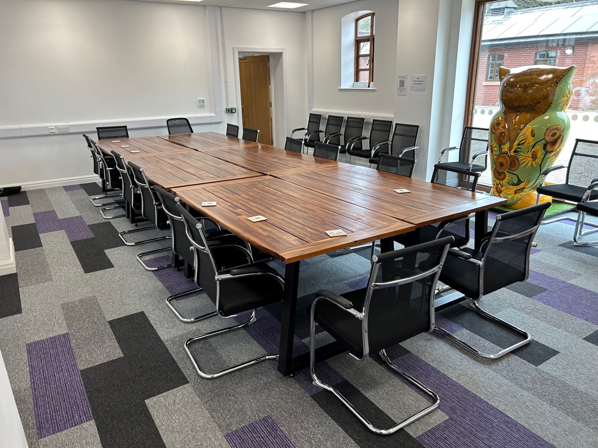 Meeting room at One Knowsley, featuring a polished wooden table and vibrant artwork.