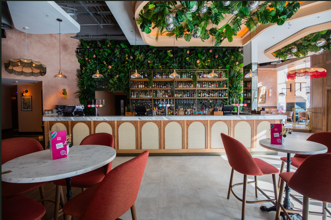 Vibrant event venue in The Palm House with stylish bar and greenery backdrop.
