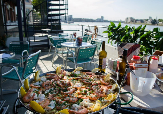 Outdoor dining at Trafalgar Rowing Centre with seafood paella for summer events.
