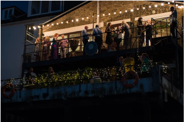 Trafalgar Rowing Centre evening event with string lights and guests mingling outdoors.