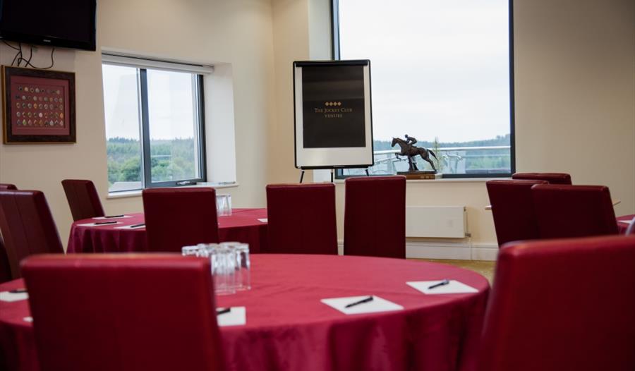 Exeter Racecourse meeting room with red tables, ideal for workshops and conferences.