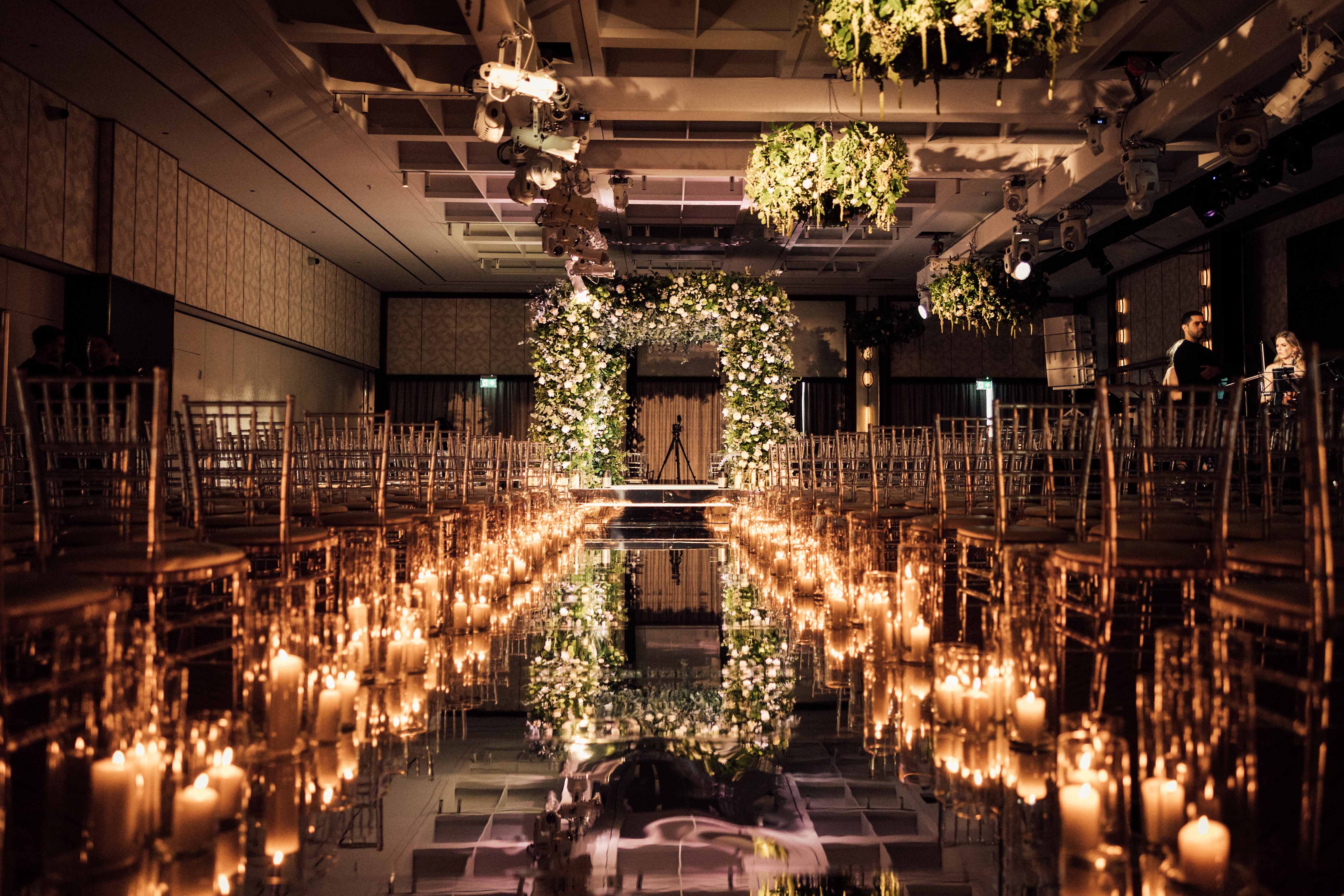 Elegant wedding ballroom at Nobu Hotel with floral arch and candlelit aisle.