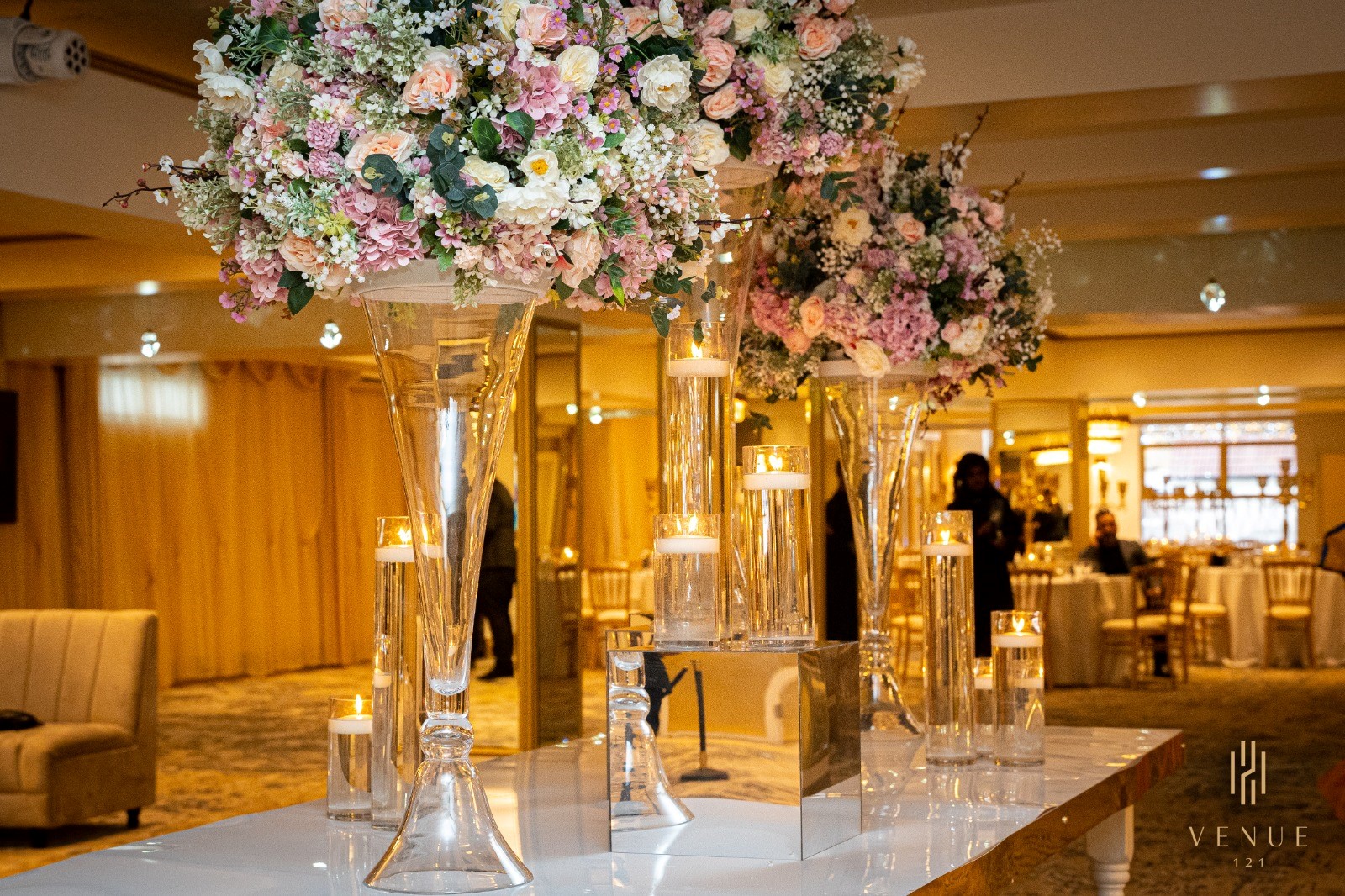 Elegant ballroom with tall floral centerpieces, perfect for weddings and upscale events.