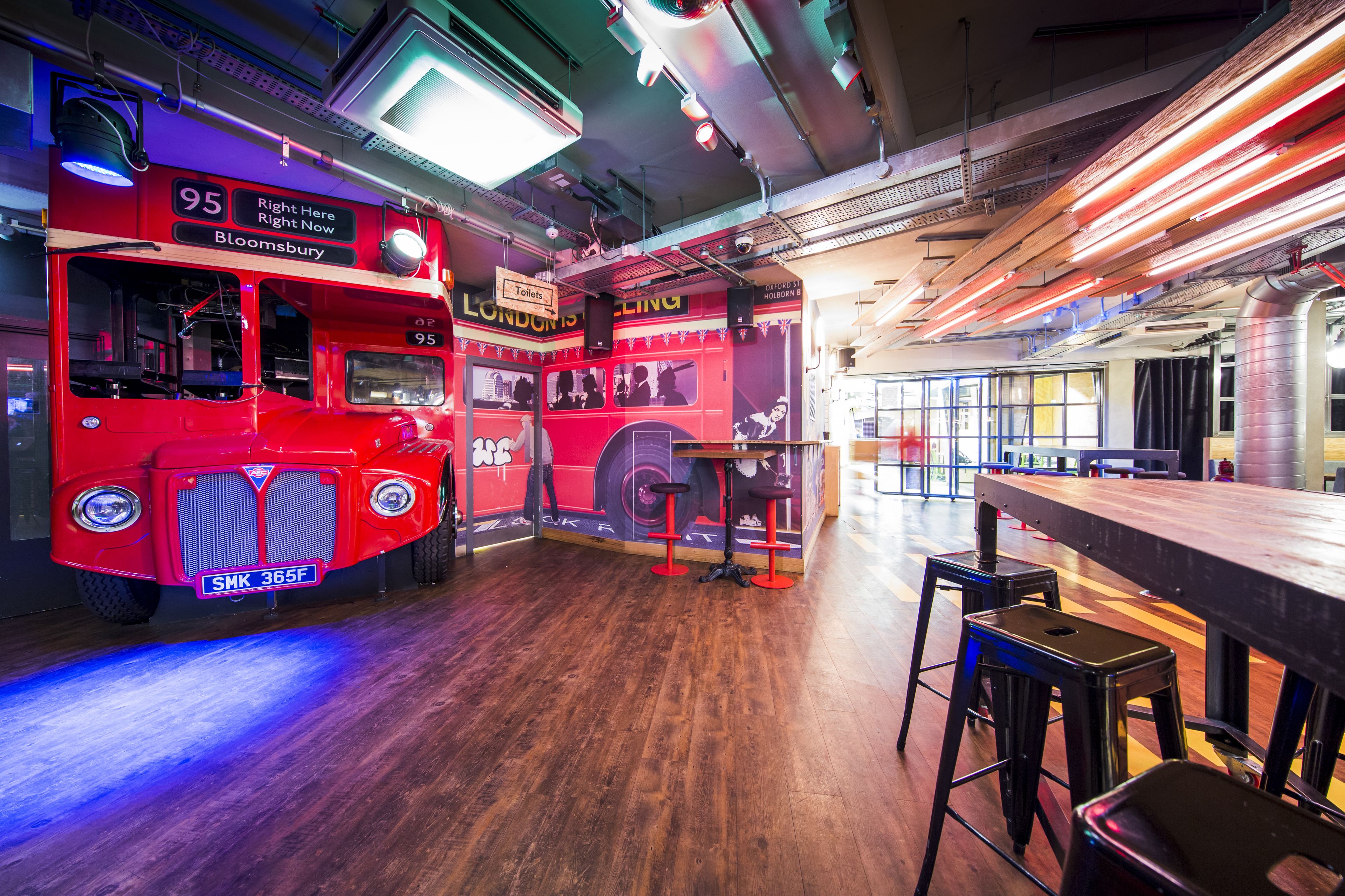 Vibrant Shuffleboard Bar London with red double-decker bus, ideal for events and gatherings.