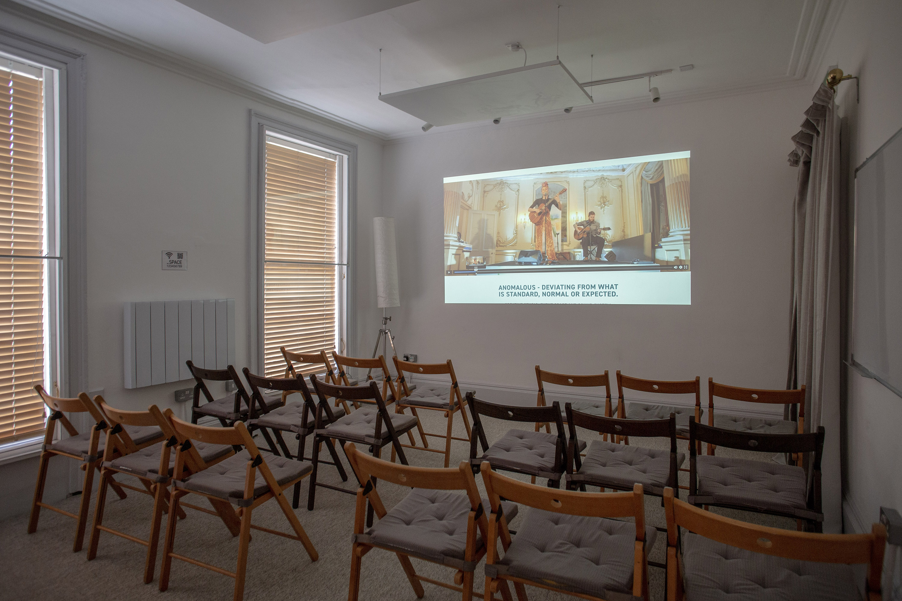 Minimalist meeting space with wooden chairs for presentations in Anomalous Space.