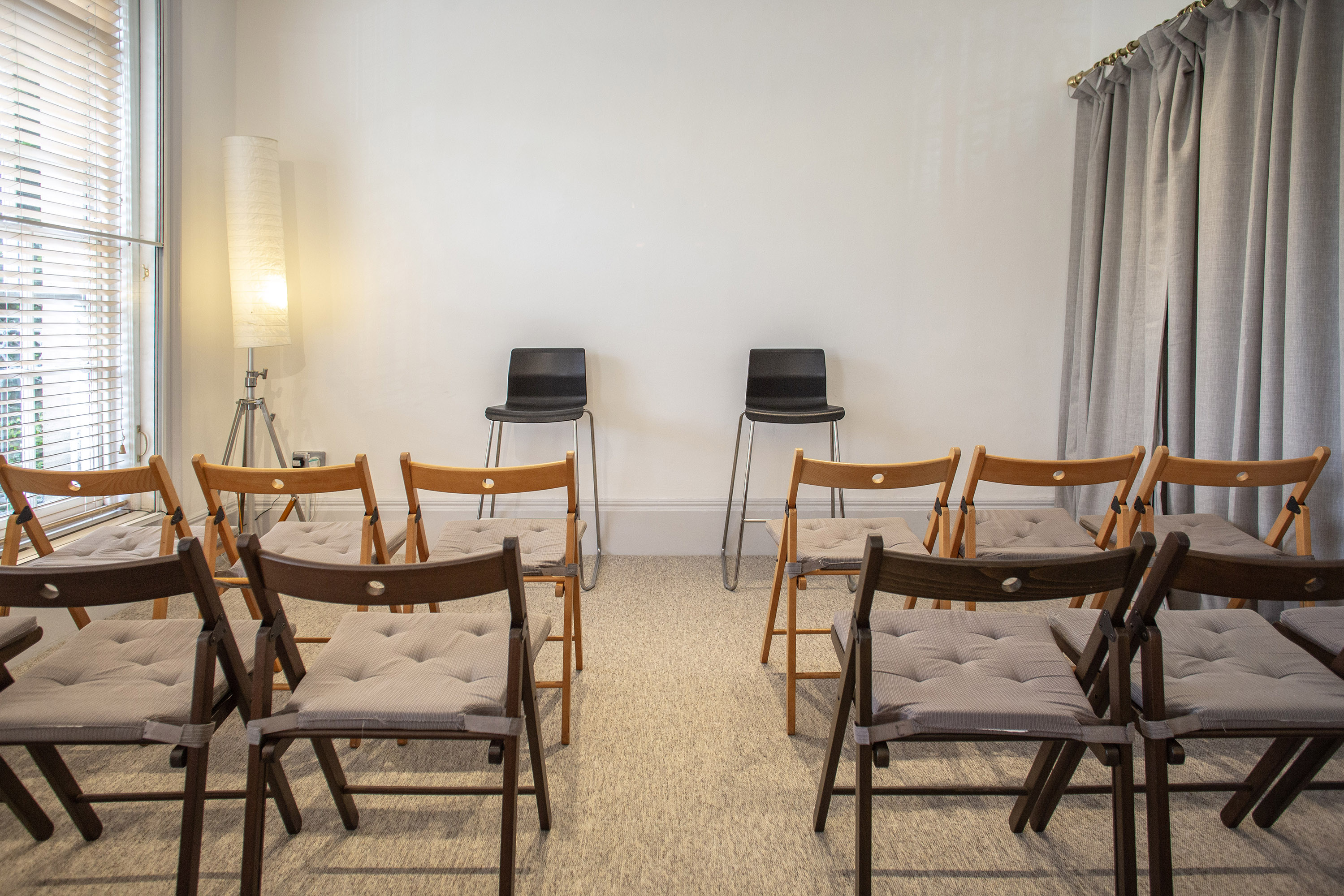 Minimalist meeting space with folding chairs for intimate workshops and team gatherings.
