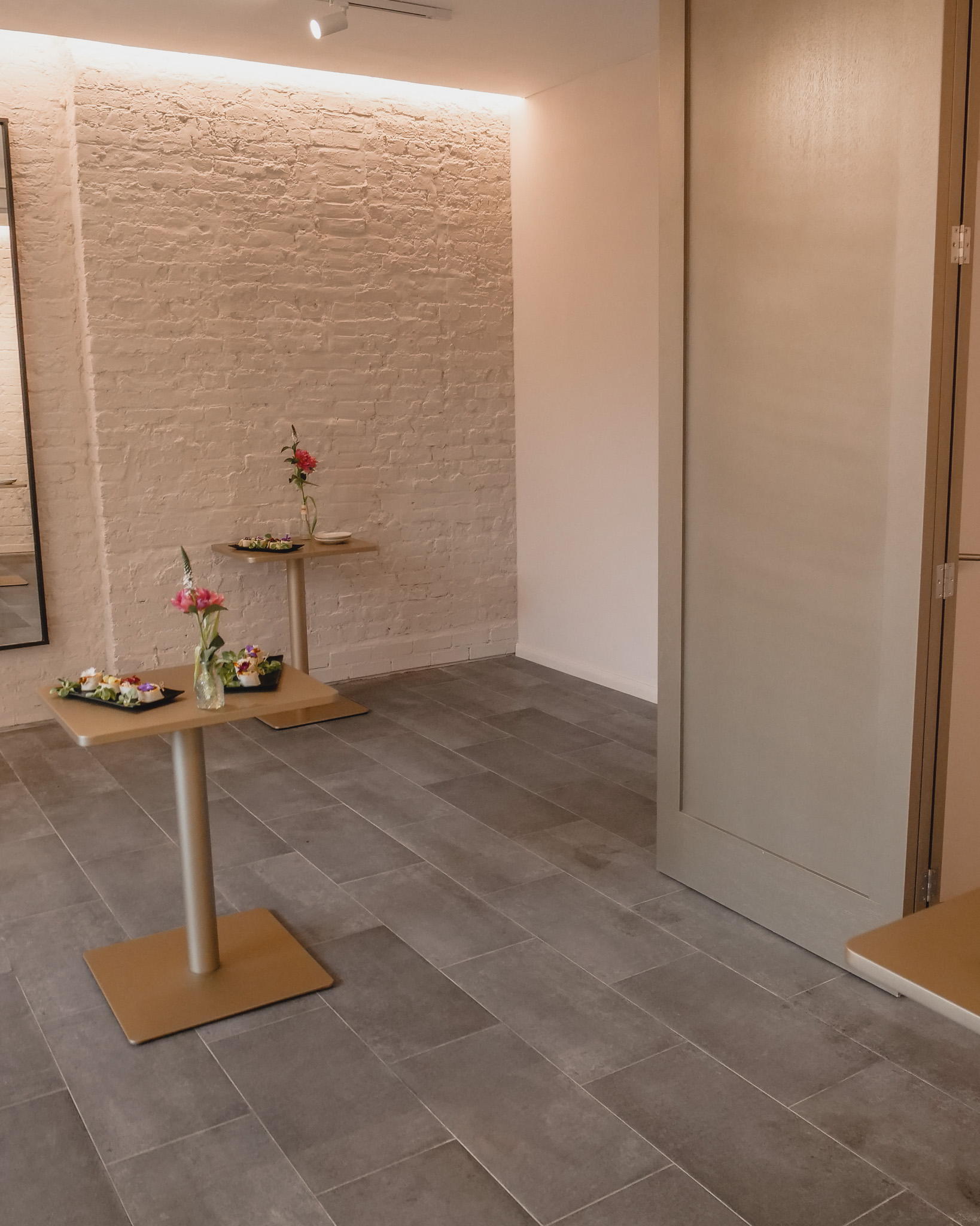 Minimalist event space with wooden tables and floral decor, perfect for gatherings or networking.