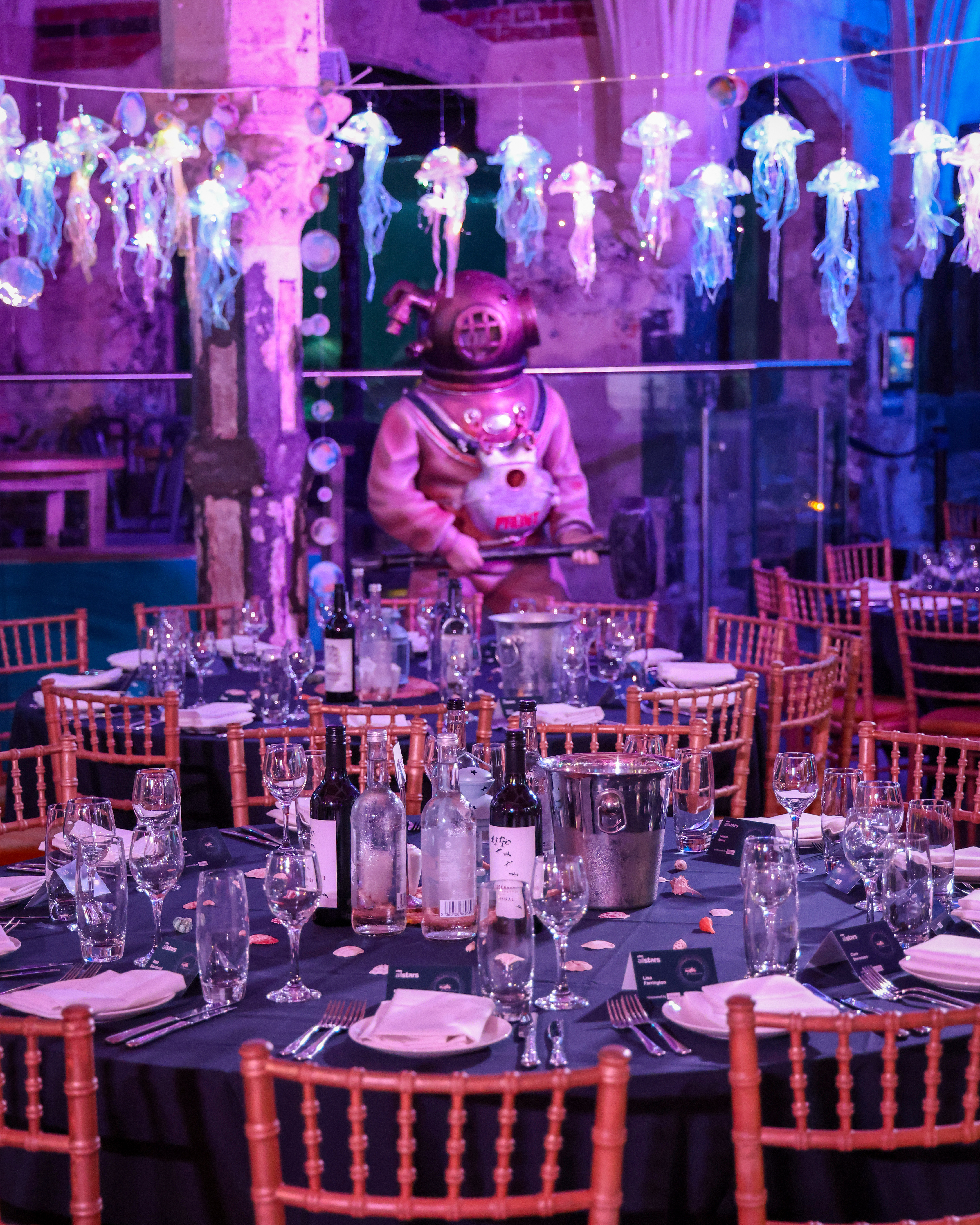 Elegant dining setup in SEA LIFE Brighton Aquarium with vintage diving suit centerpiece.