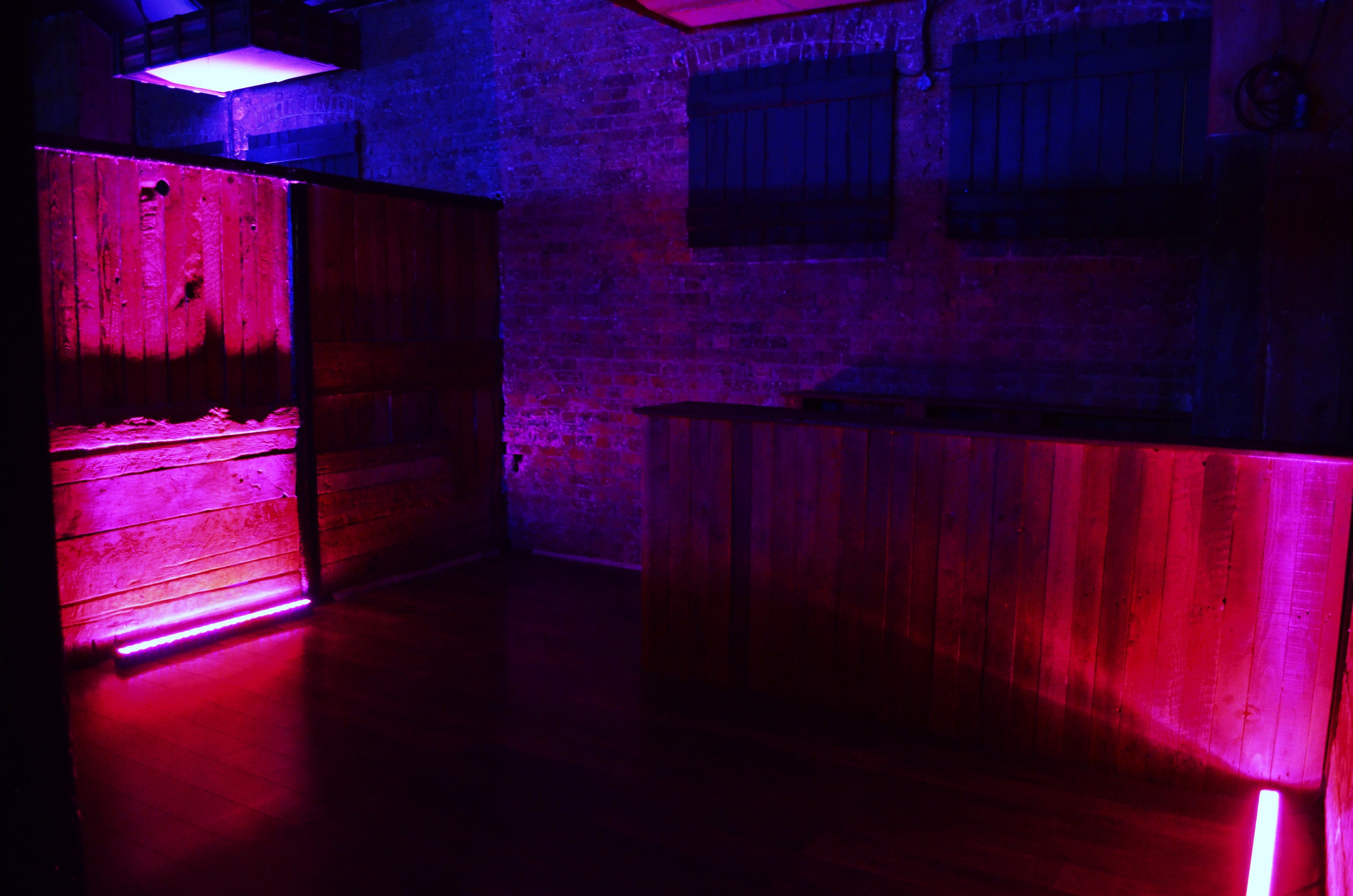 Creative event space at The Warehouse, Camden with wooden elements and vibrant purple lighting.