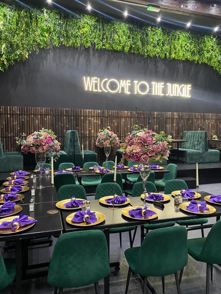 Vibrant Jungle Bar & Grill event space with neon sign, perfect for upscale gatherings.