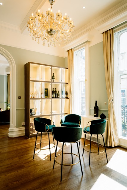 Stylish meeting space at VCLUB Whisky Lounge with elegant green chairs and whisky display.